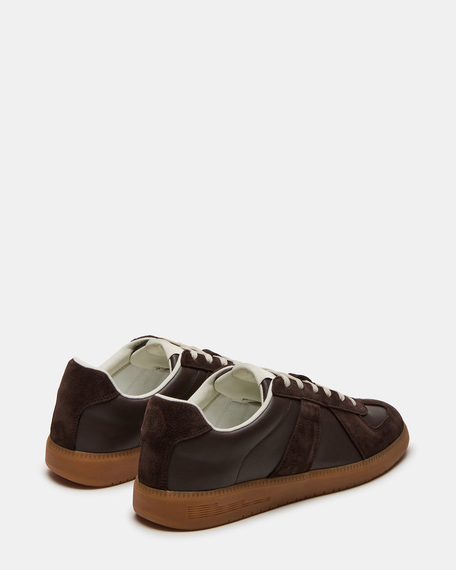 Close-up heel shot of black leather sneakers on a concrete backdrop