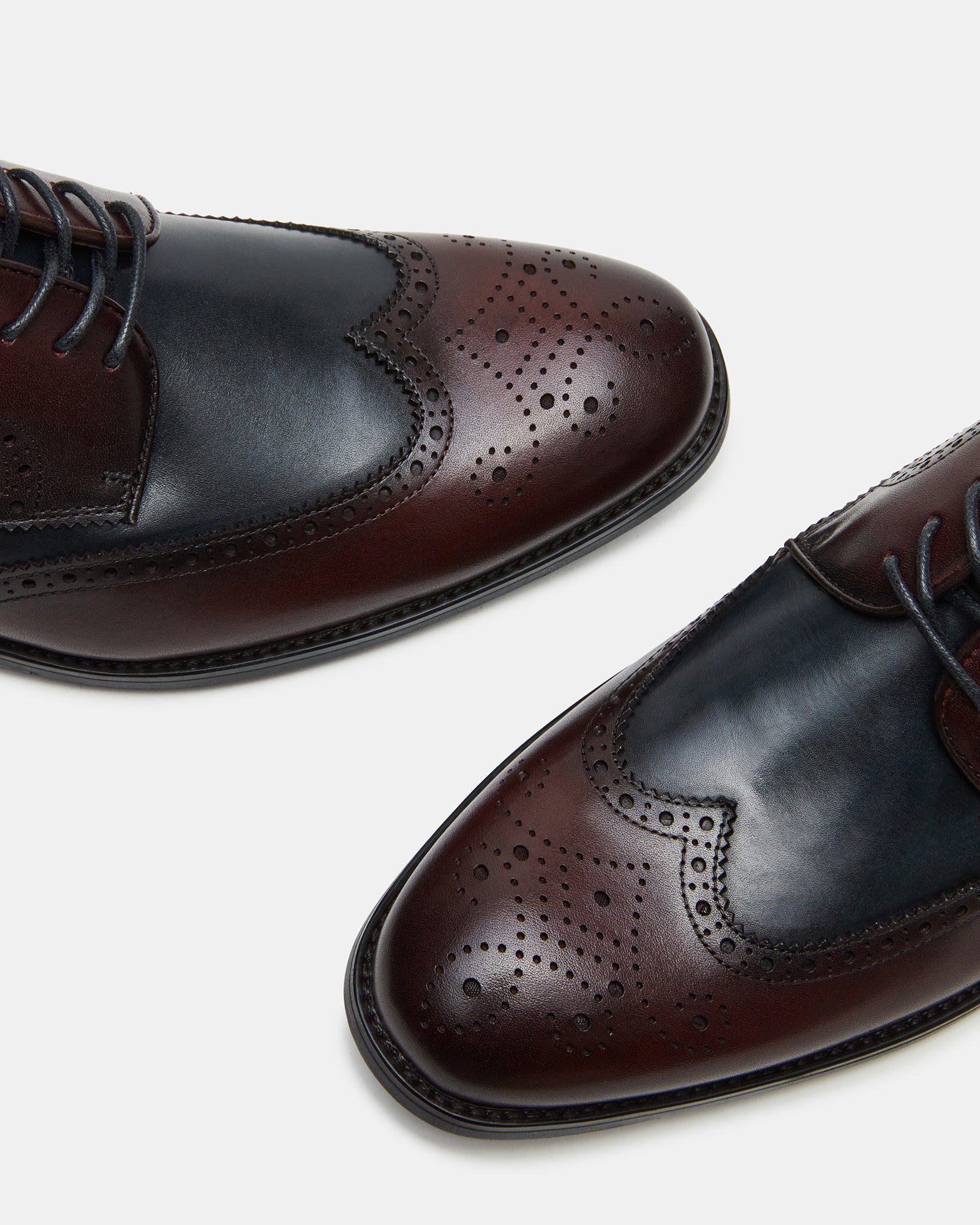Lifestyle shot showing wingtip shoes worn on London cobblestone street.