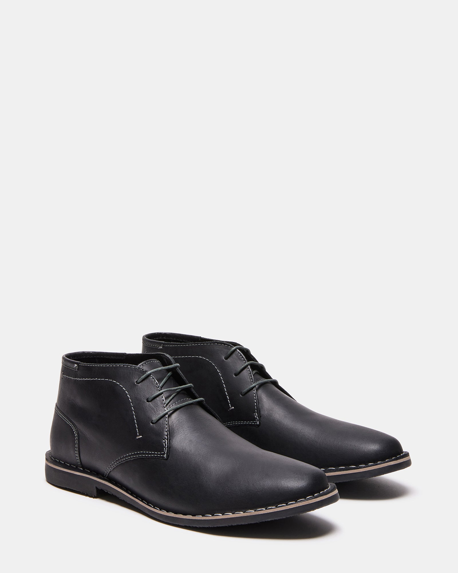 Side profile of mens lace-up boots on urban concrete backdrop.