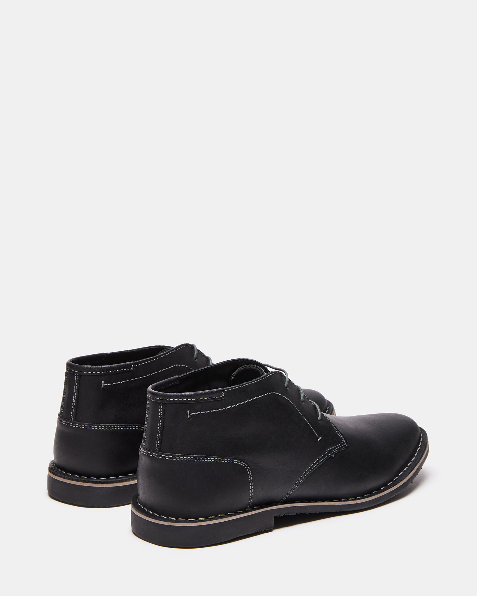Side profile of mens lace-up boots on urban concrete backdrop.