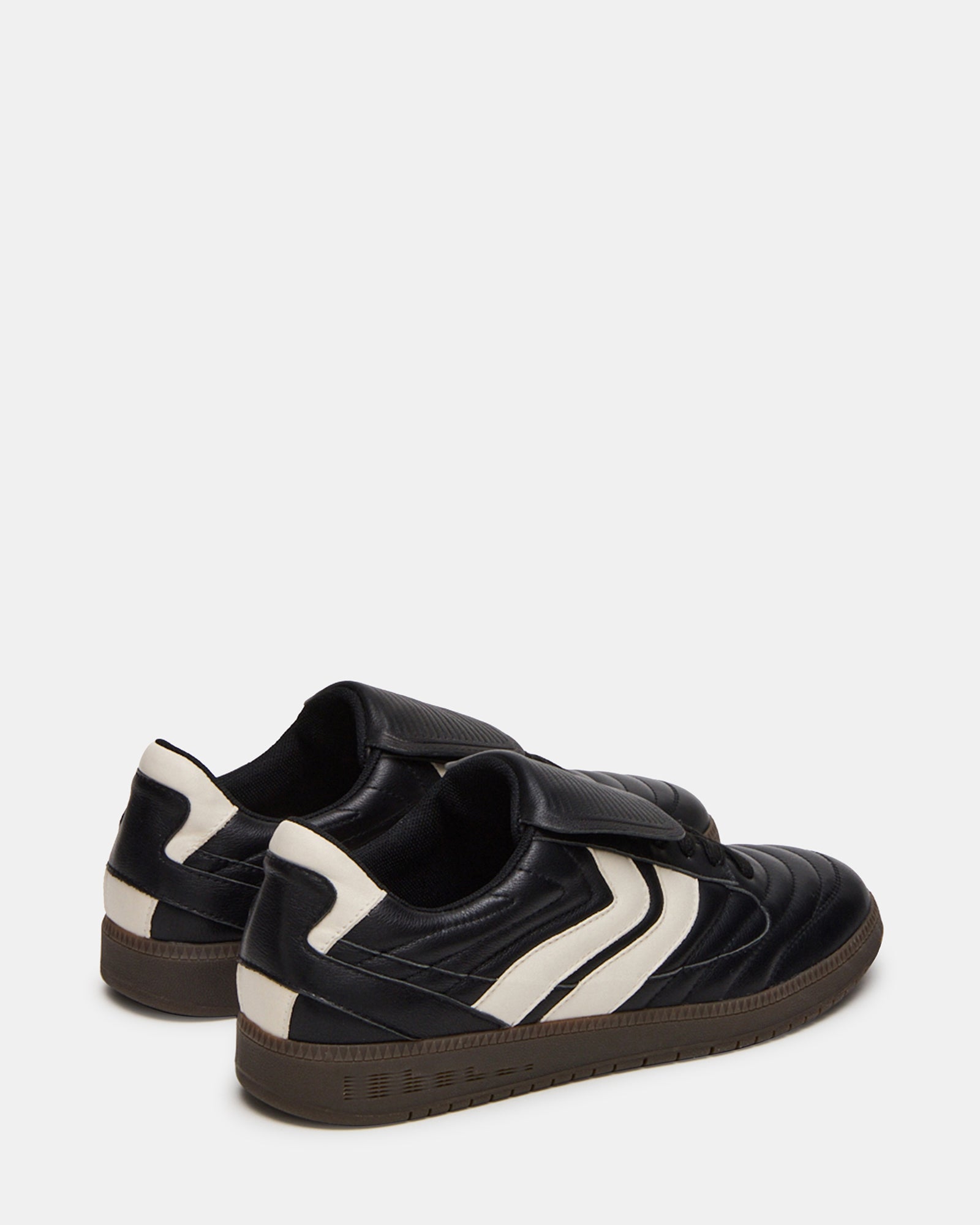 Mens black leather sneakers worn casually with rolled jeans in an urban setting