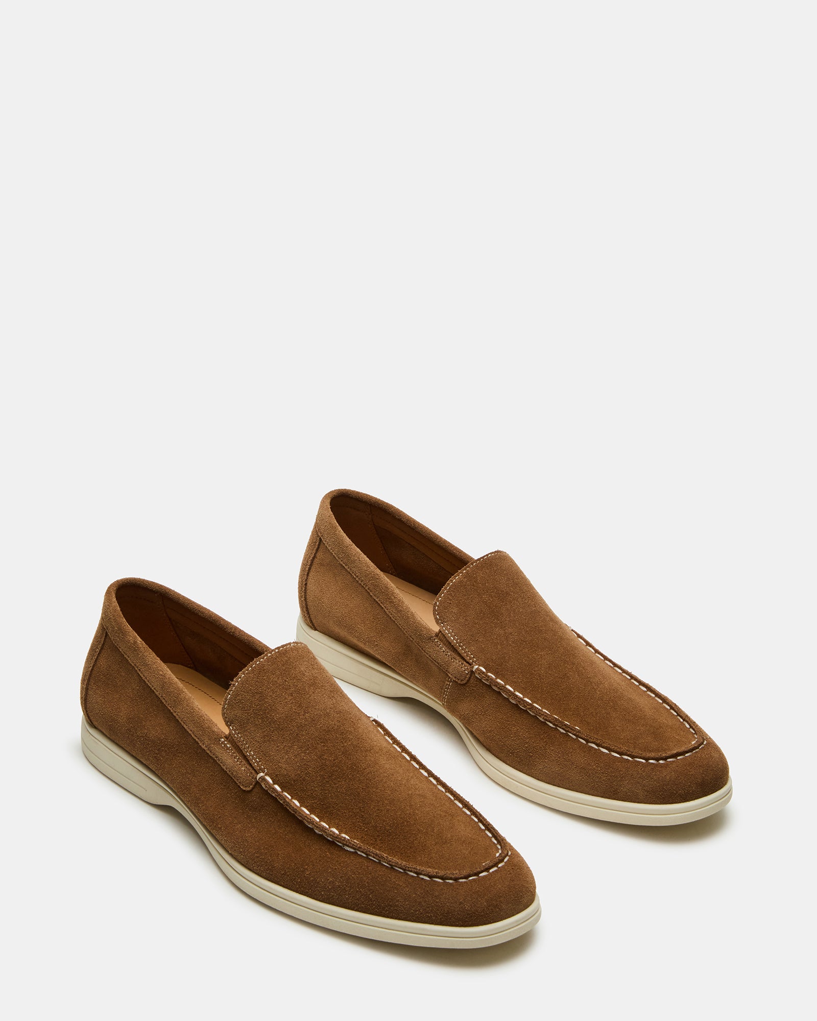 Men wearing LINUX brown suede slip-on shoes in a casual outdoor setting.