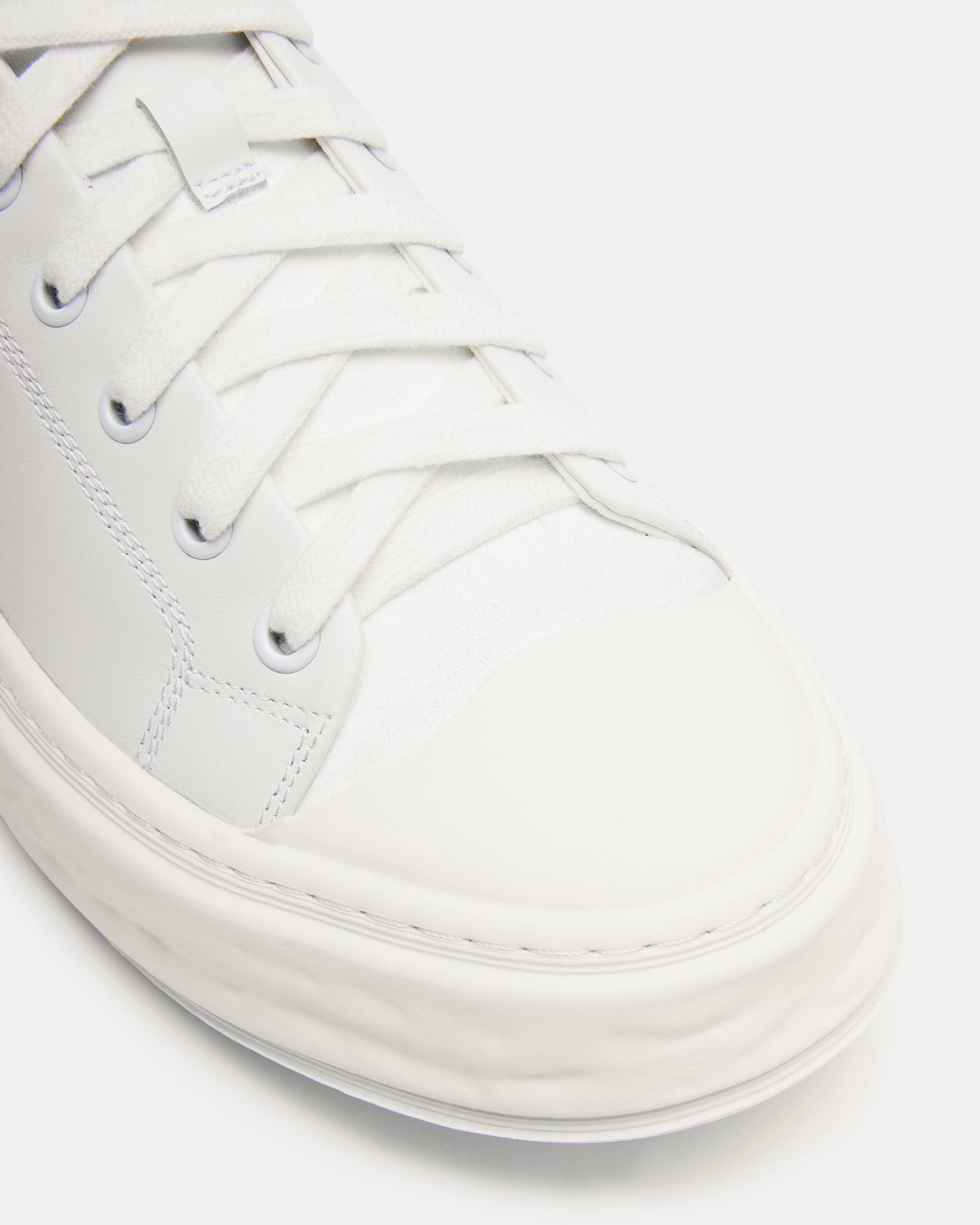 Macrae white leather sneakers displayed on a casual outfit background.