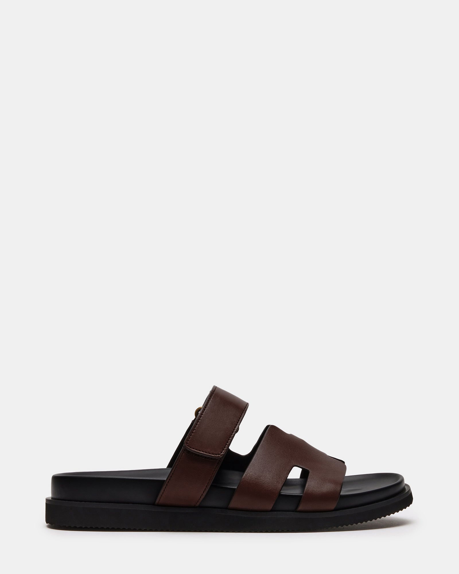 Side view of Maiven brown leather sandals on a wooden deck, showcasing the slip-on design