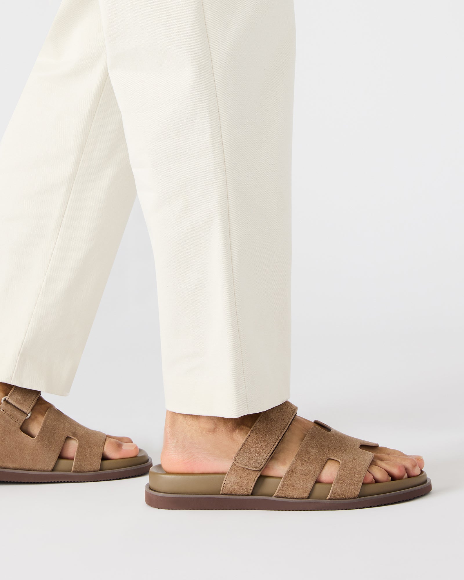 Model wearing taupe suede slides at a summer beach party, demonstrating versatility.