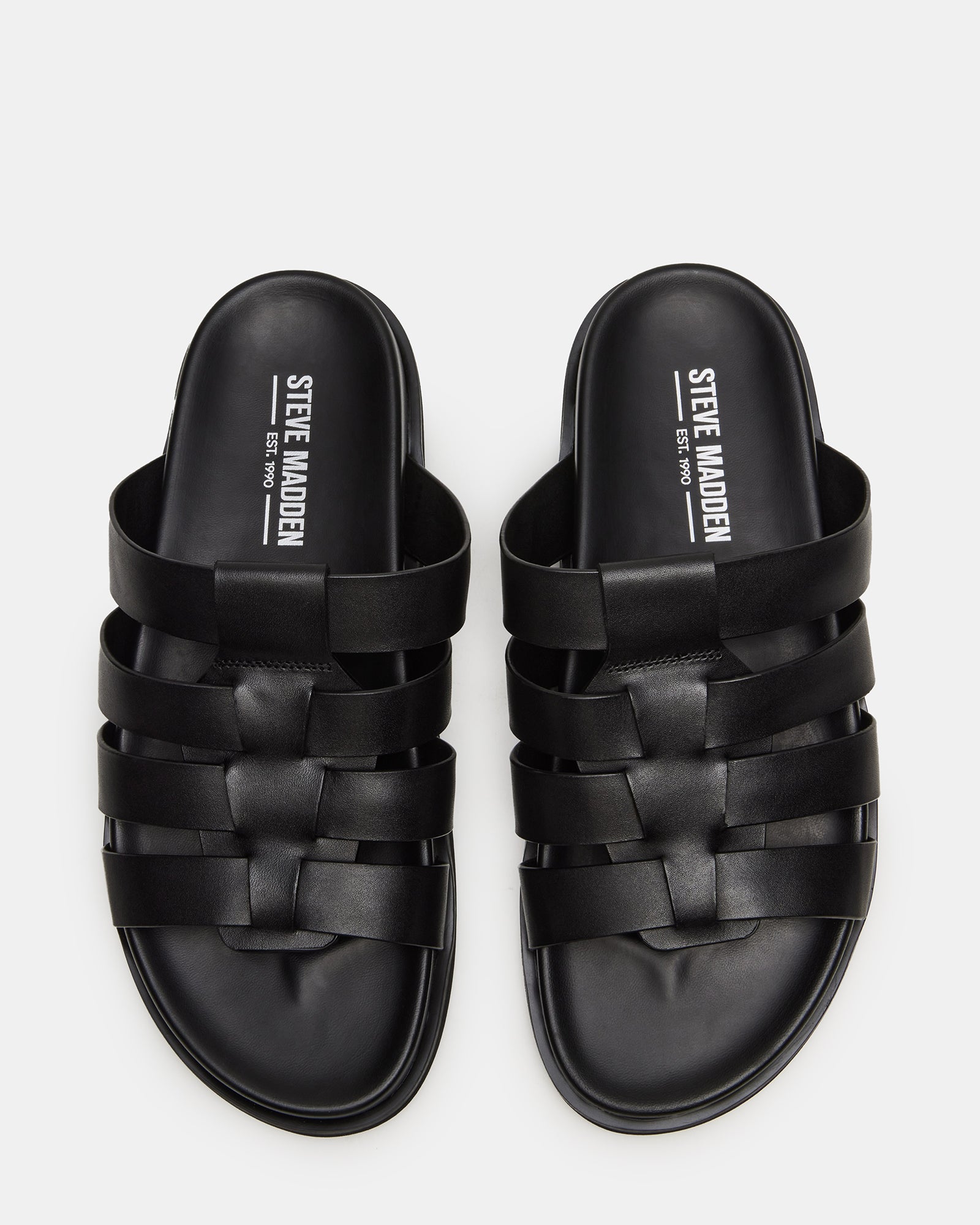 Marvyn black leather sandals on a rustic wooden background
