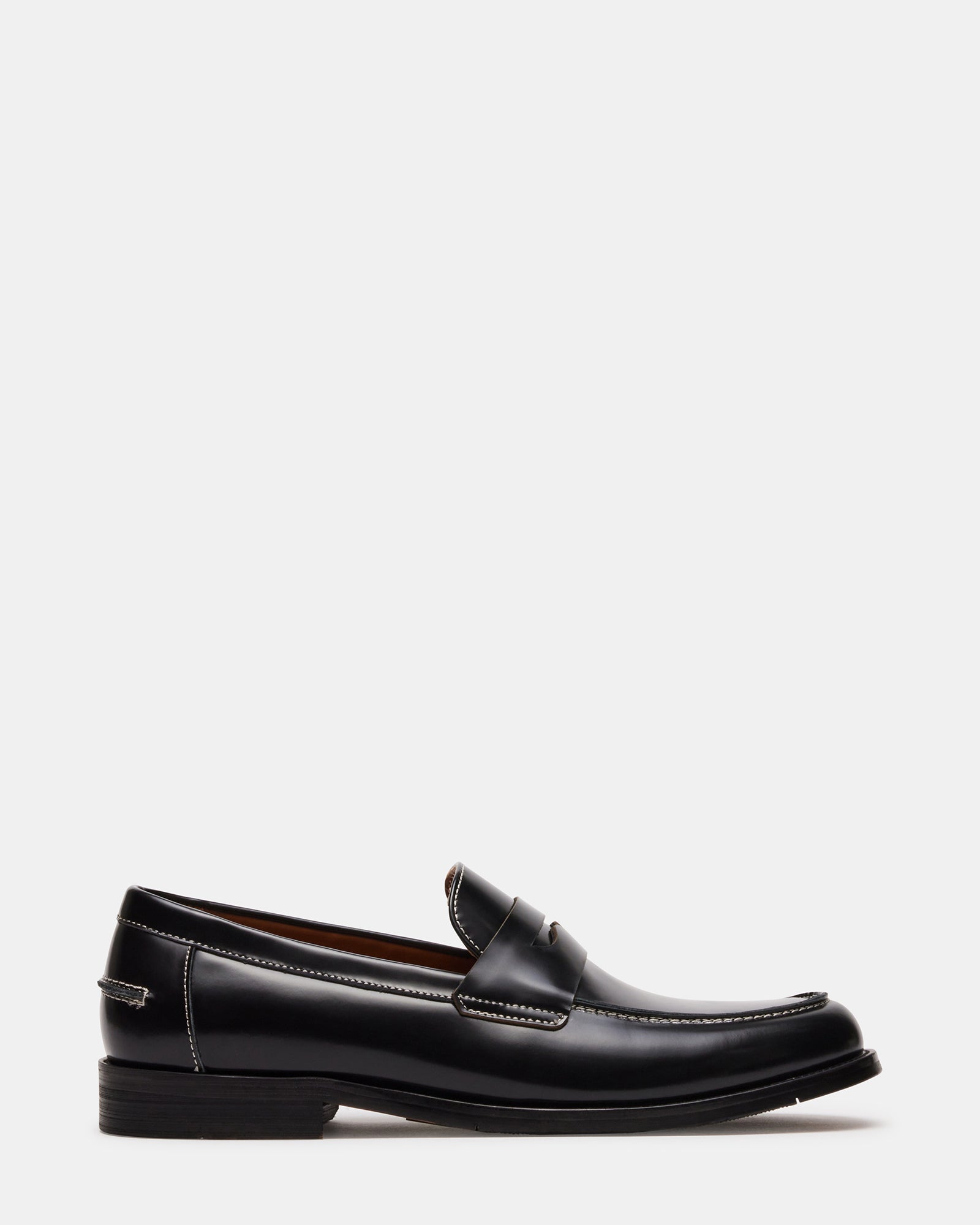 Side view of Natan men's black leather loafers in a bright office setting.