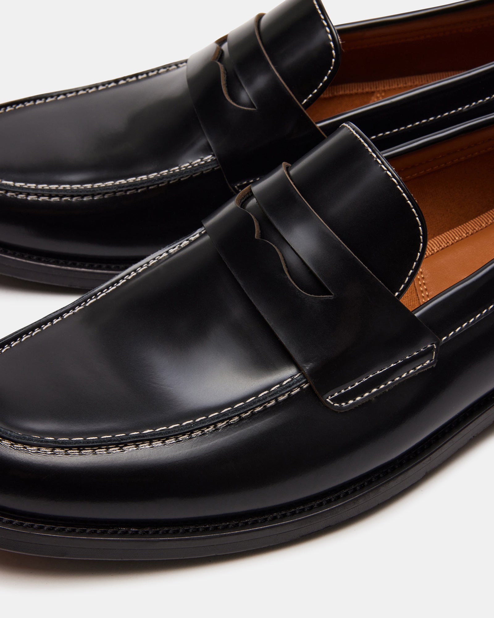 Side view of Natan mens black leather loafers in a bright office setting.