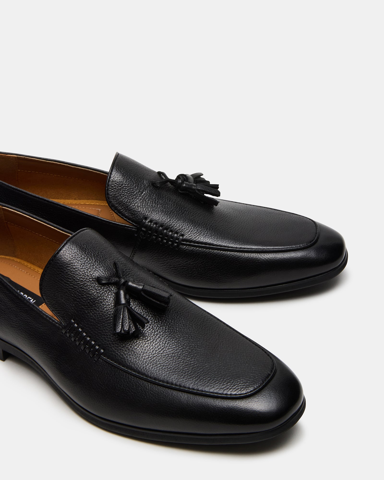 Close-up of ONDRE black leather loafers showcasing tassel detail.