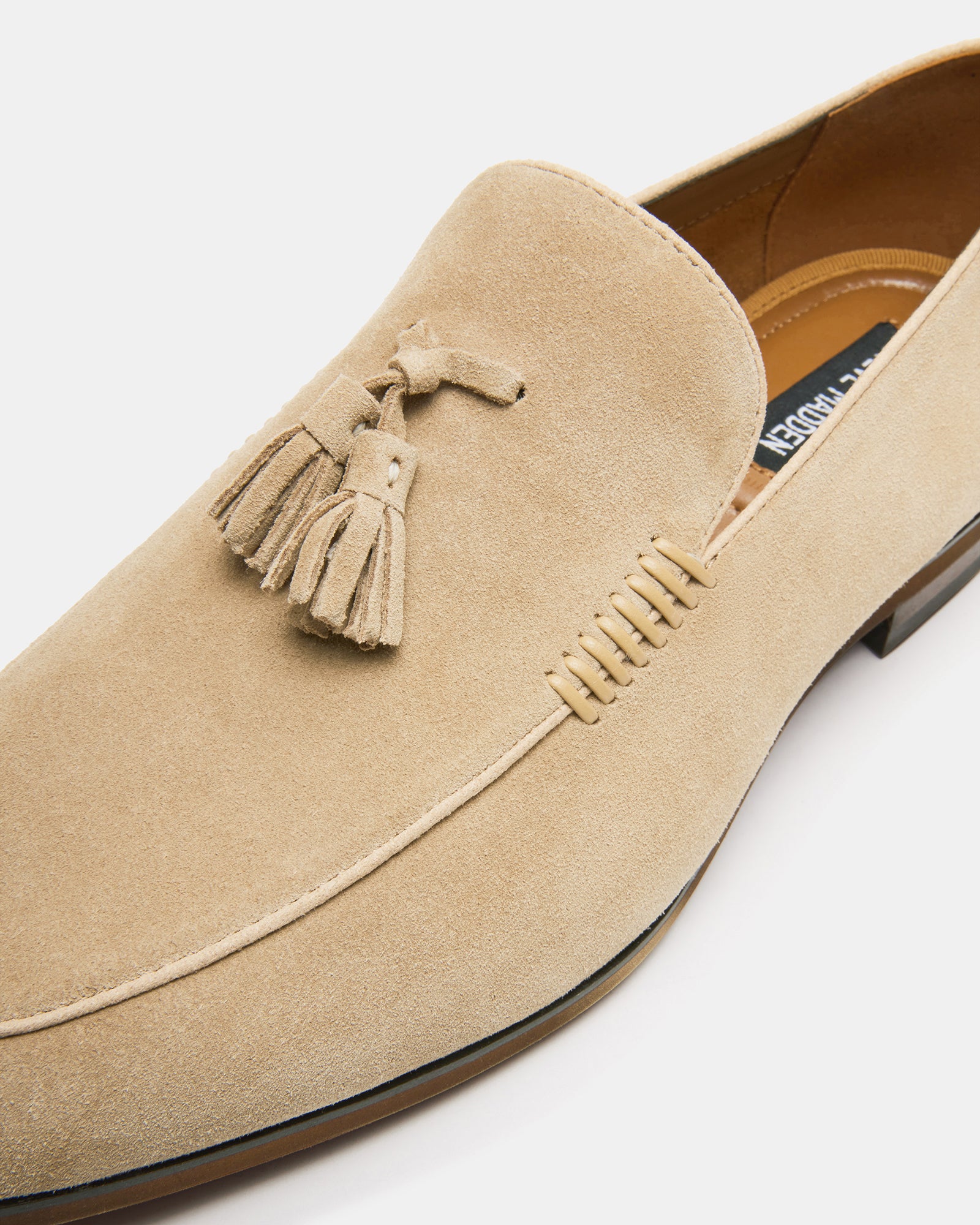 Close-up of mens sand suede loafers showing tassel and almond toe design