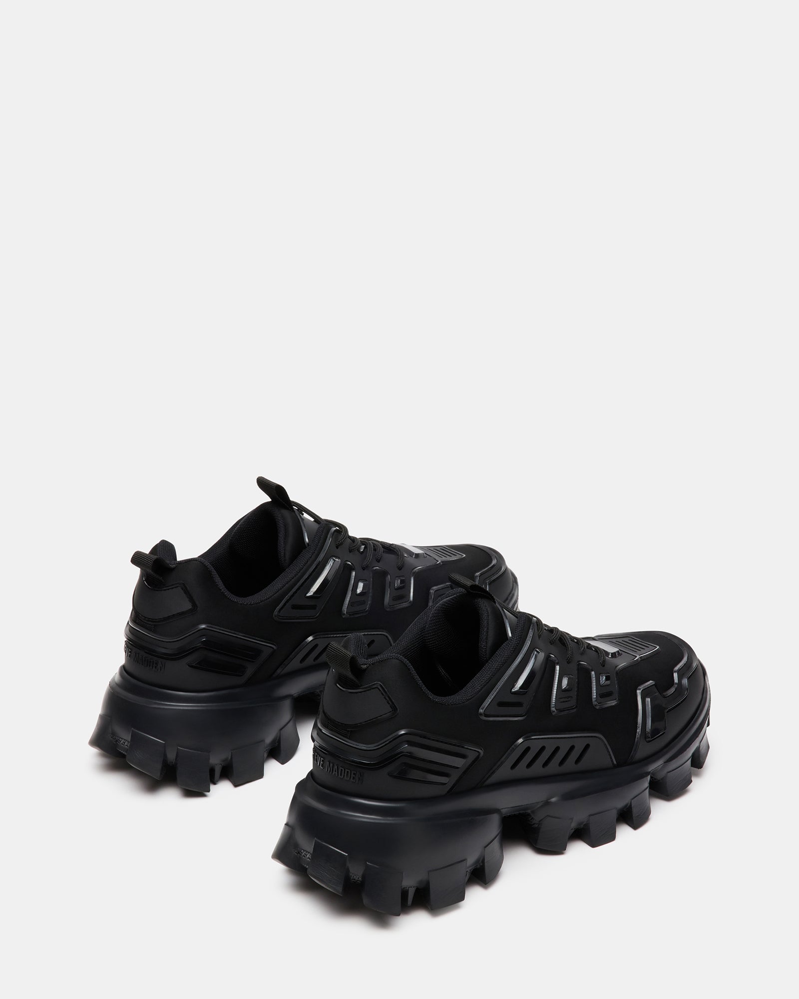 Side view of black fashion sneakers with chunky sole worn on city pavement