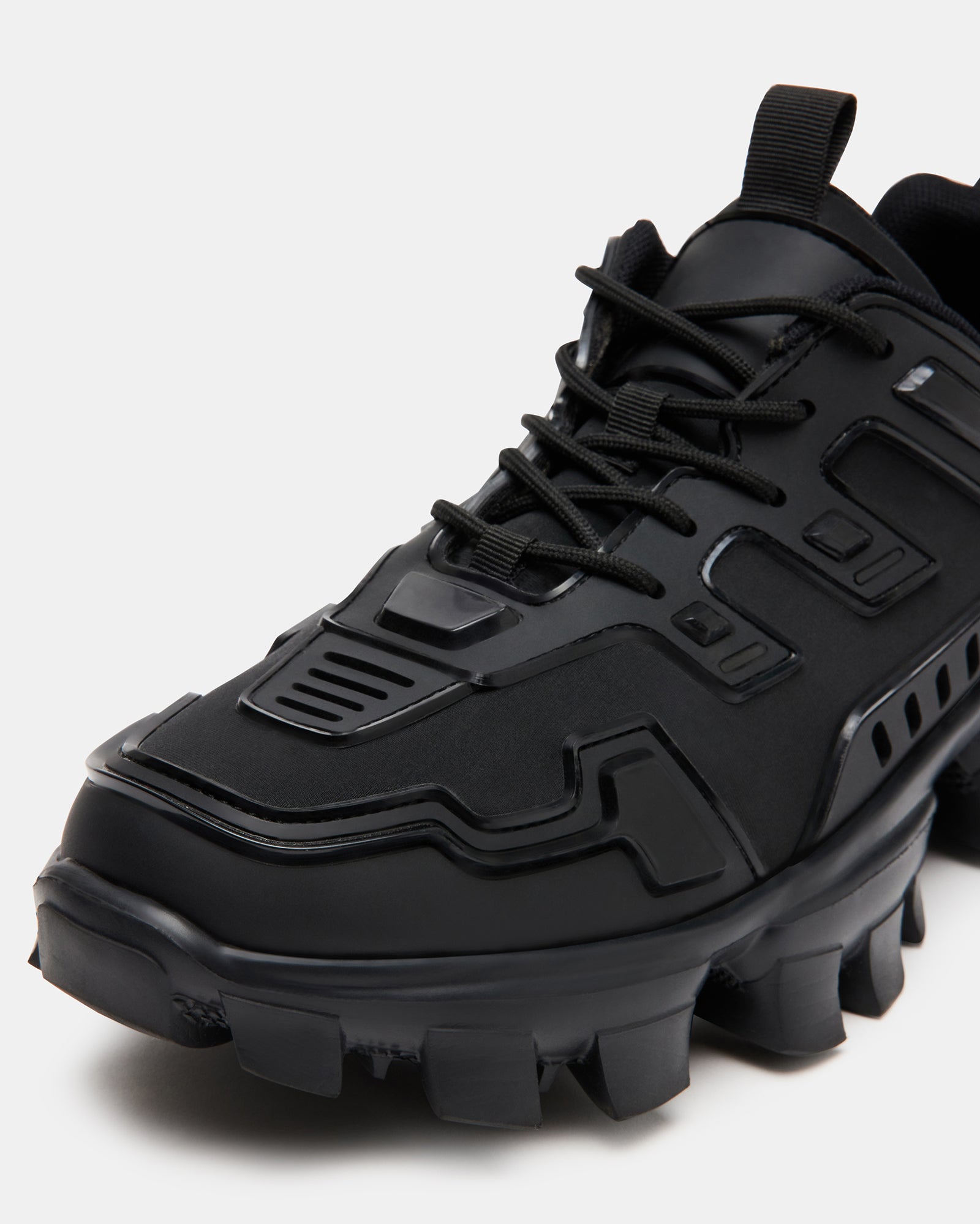 Side view of black fashion sneakers with chunky sole worn on city pavement