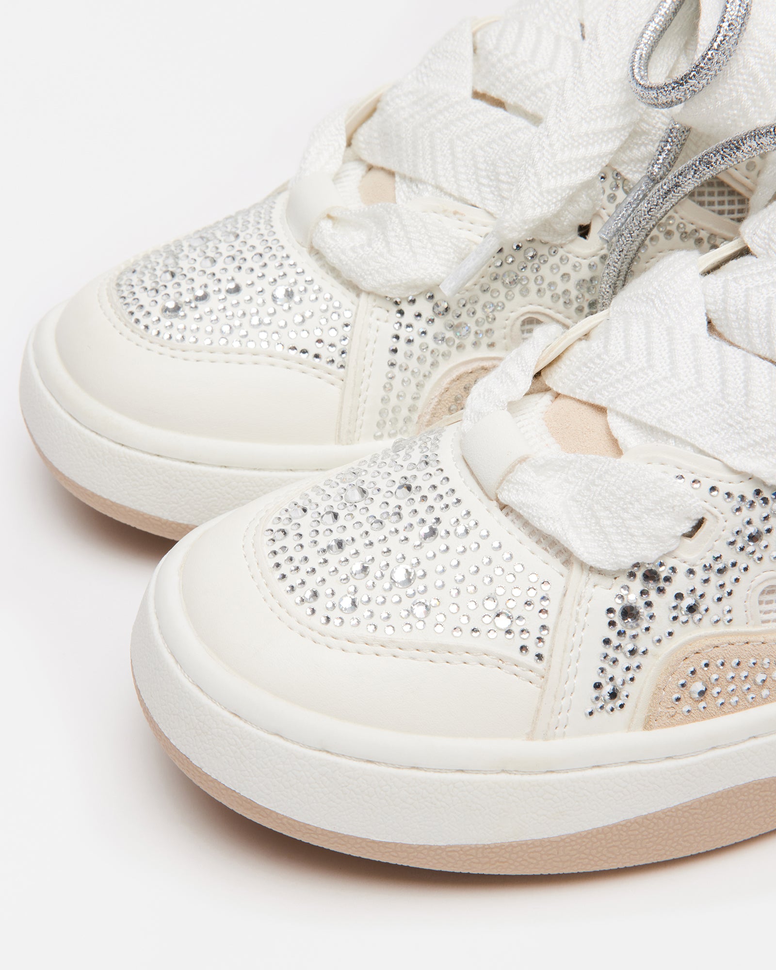 Close-up side view showing rhinestone pattern and double lacing on white platform sneakers