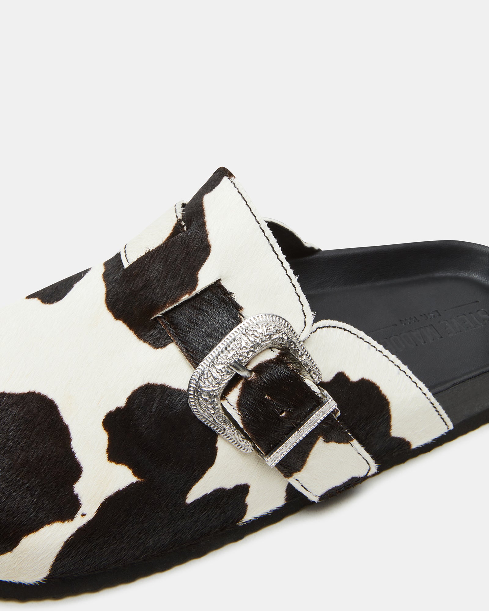 Mens casual slip-on shoes with western buckle detail on a city sidewalk