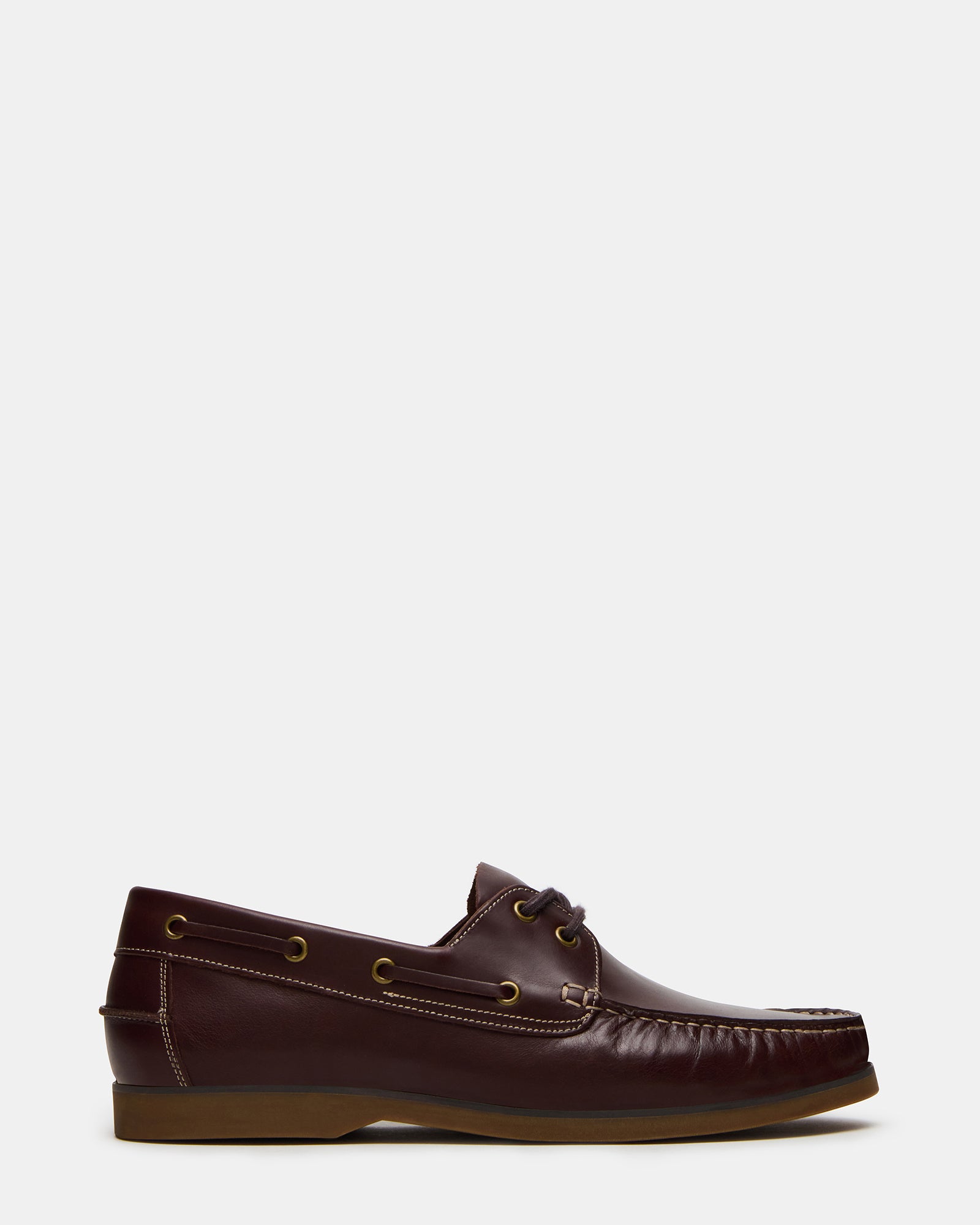 Side view of men's leather loafers styled with cuffed jeans near a marina
