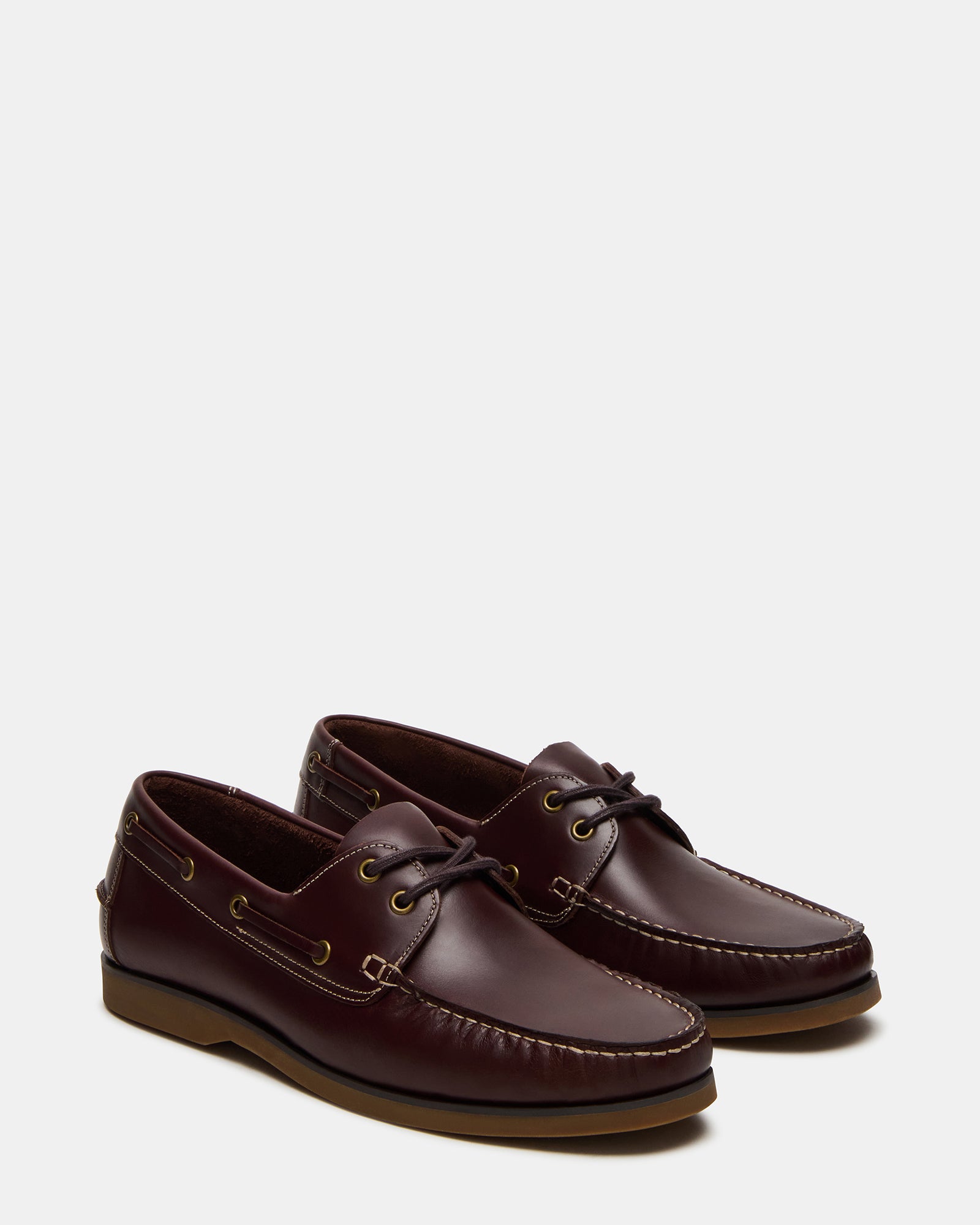 Top-down shot of brown boat shoes for women and men next to beach bag
