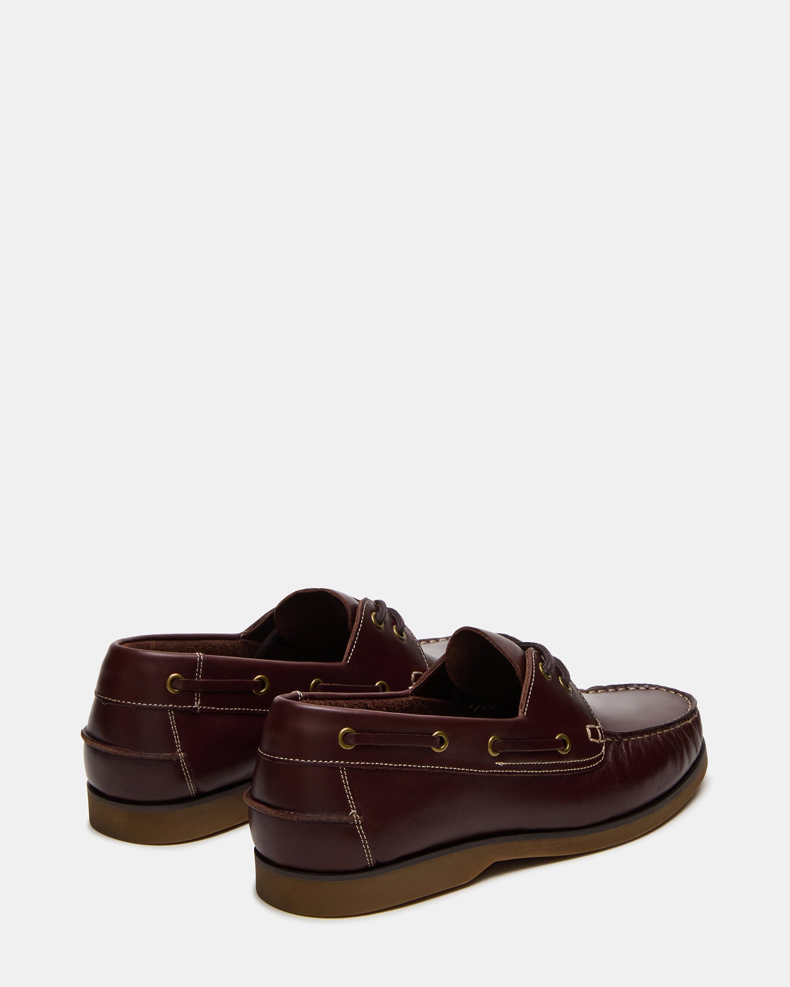 Top-down shot of brown boat shoes for women and men next to beach bag