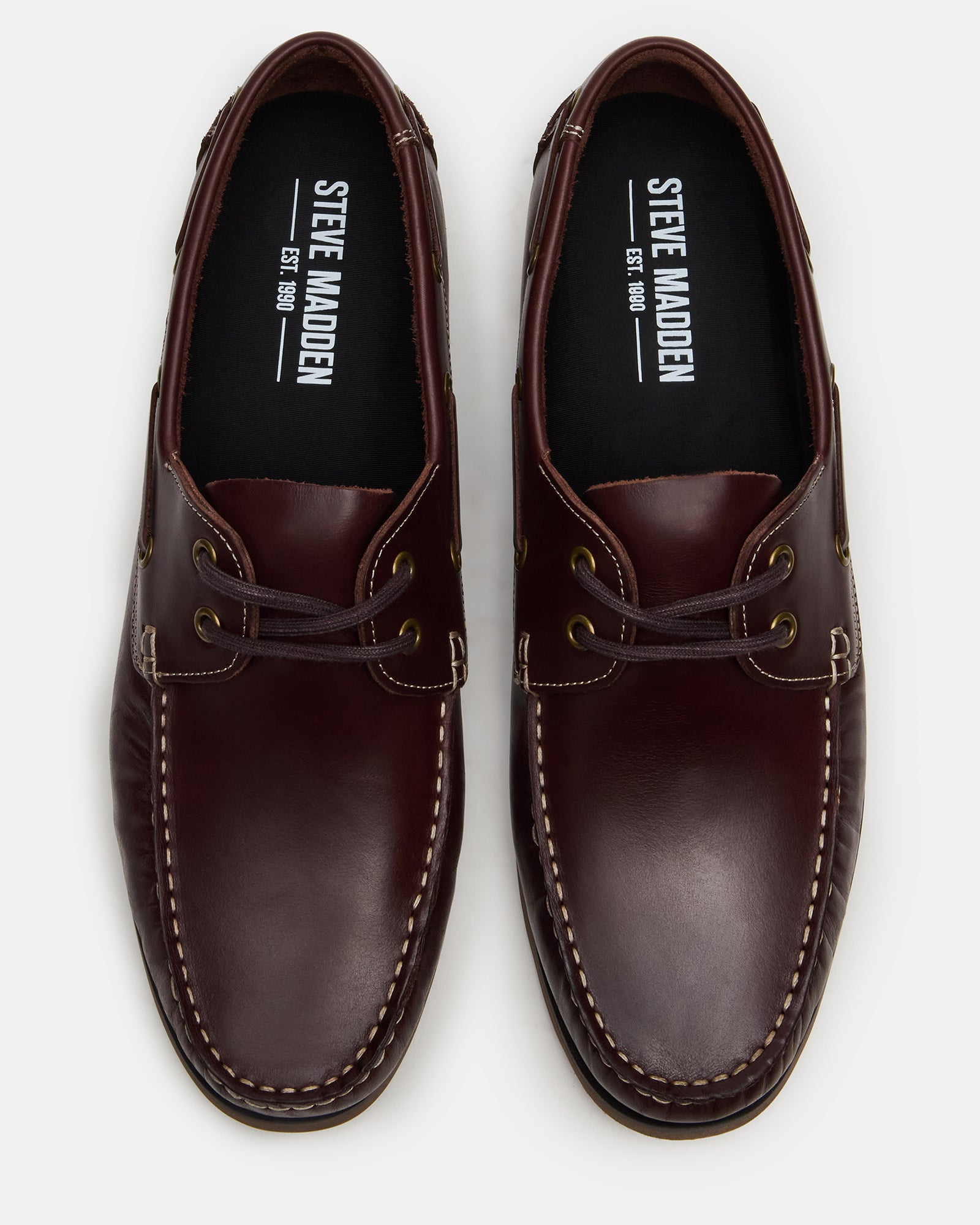 Side view of mens leather loafers styled with cuffed jeans near a marina