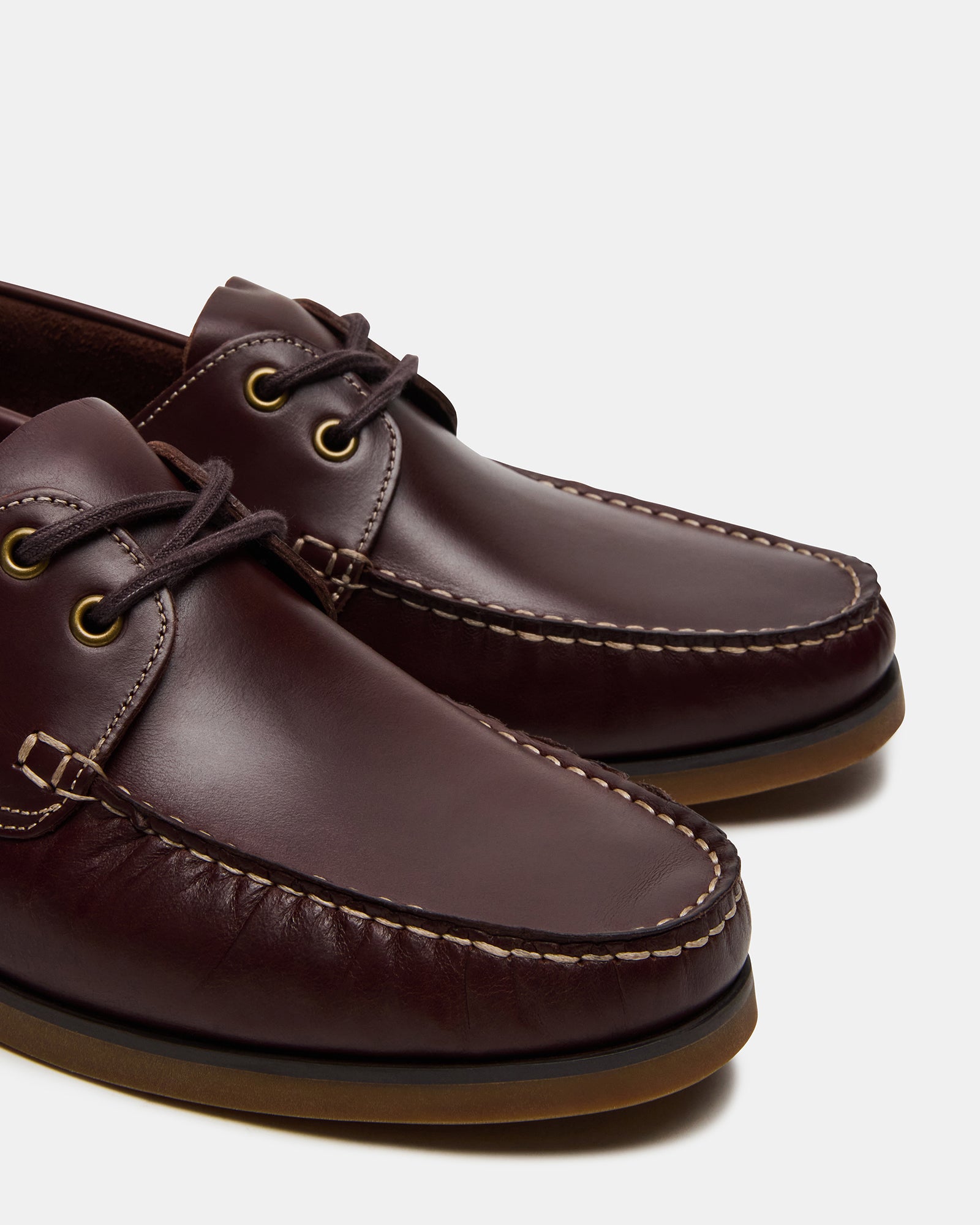 Close-up of stitched moc toe and rubber sole on slip-on loafers, shown mid-step