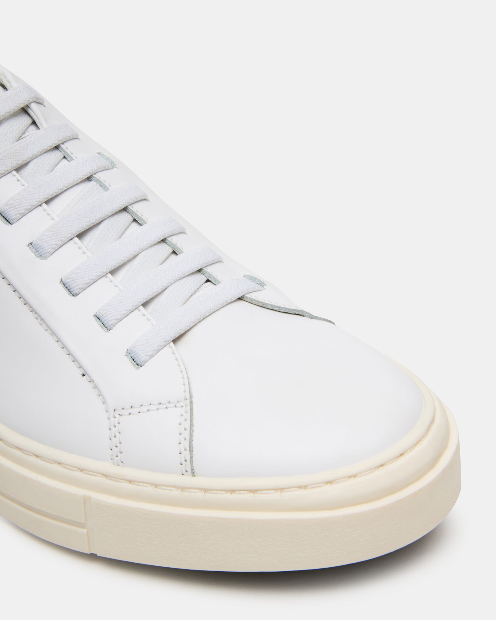 Side view of ZOII white leather sneakers highlighting the sleek design and rubber sole