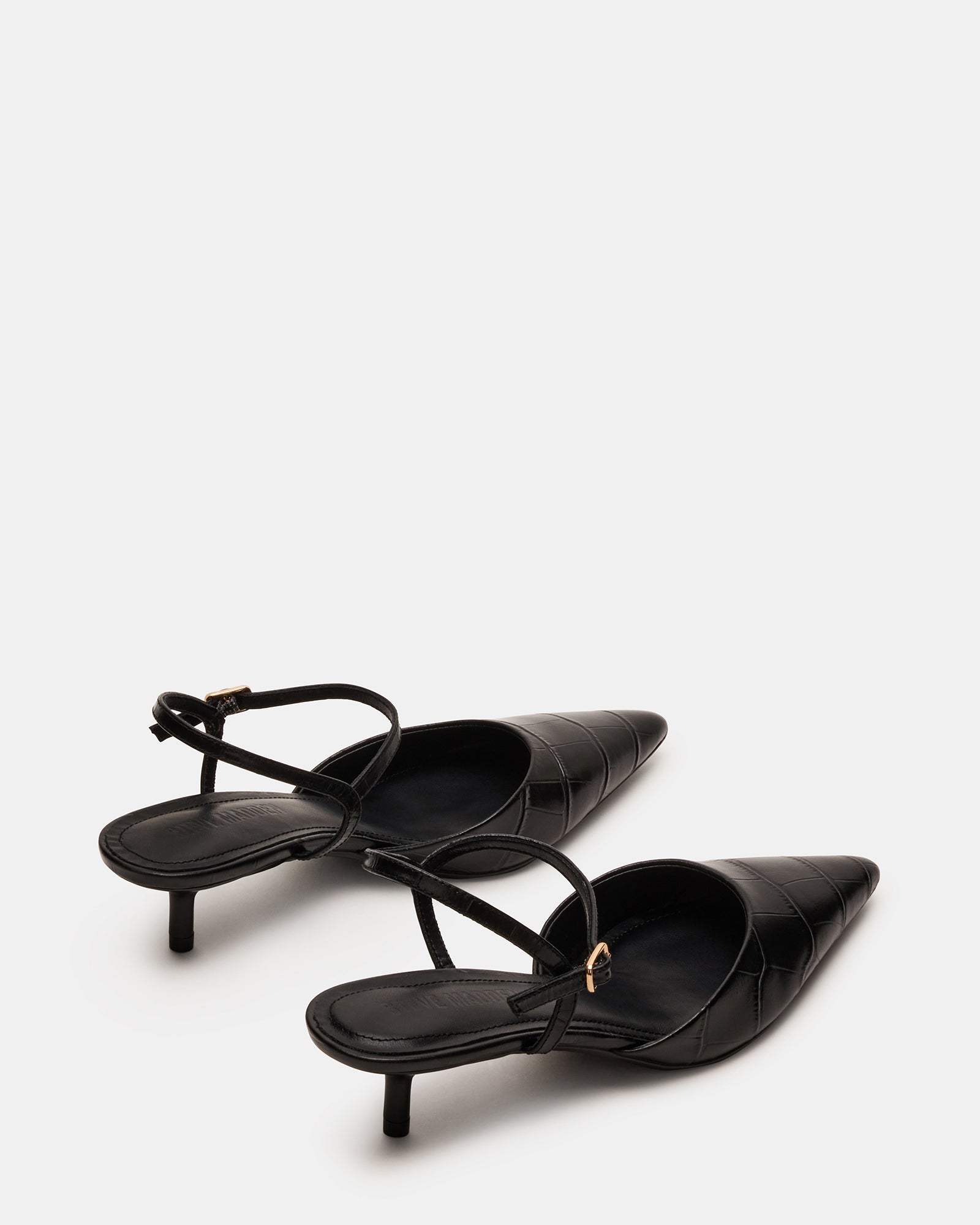 Close-up of the kitten heel on black crocodile pumps.