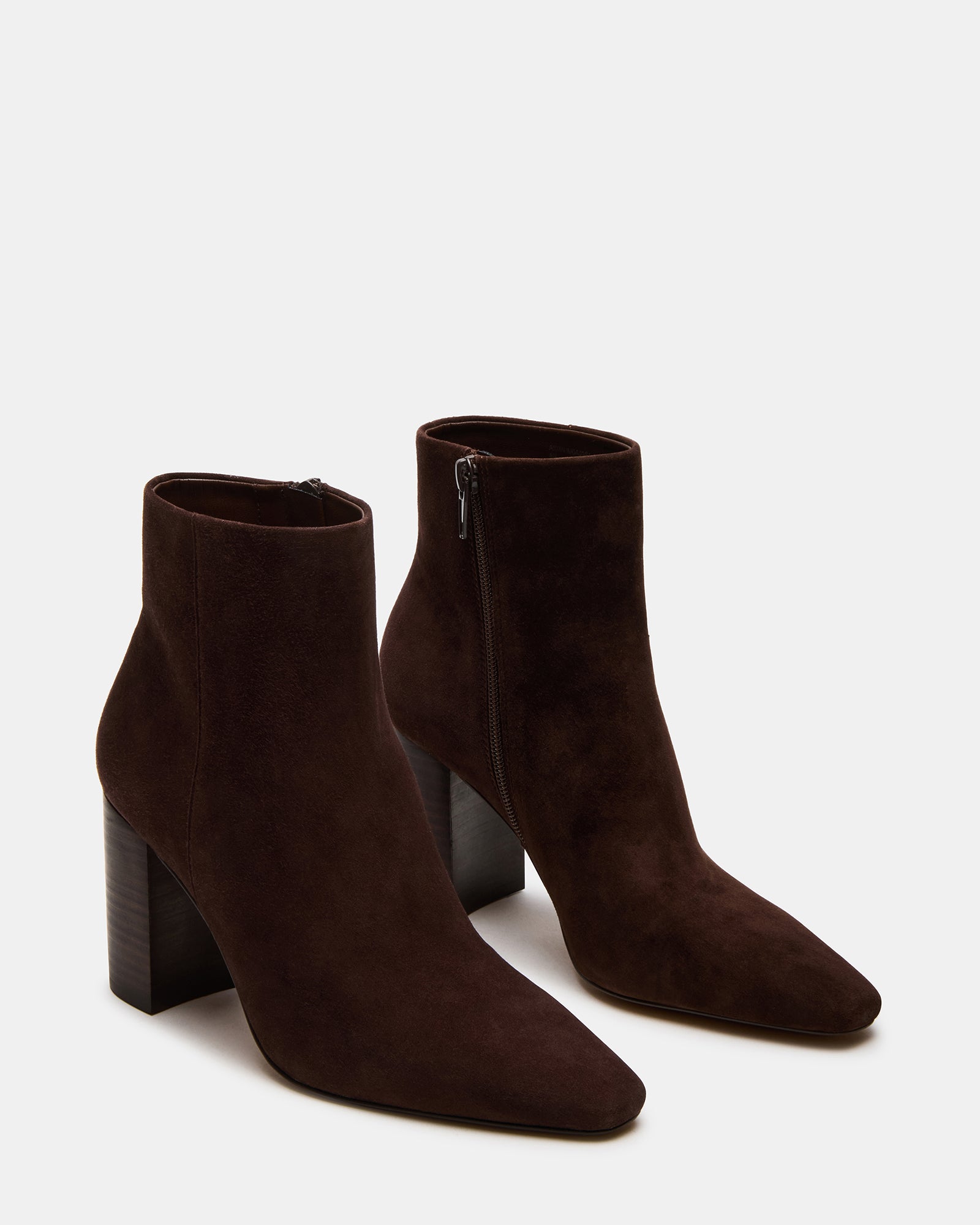 Pair of Aidan ankle boots on a rug, highlighting the suede texture and heel height