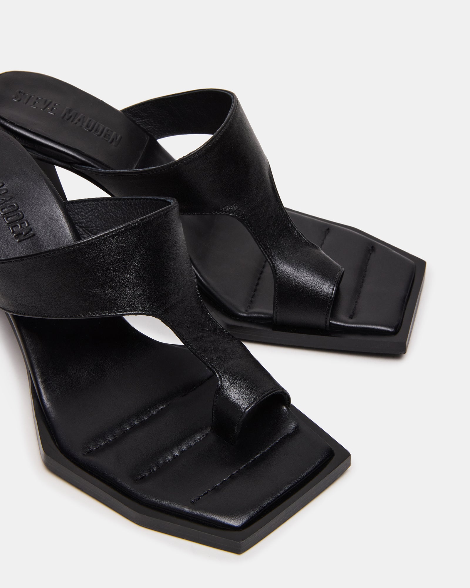 Close-up of black patent leather heels worn with jeans outdoors