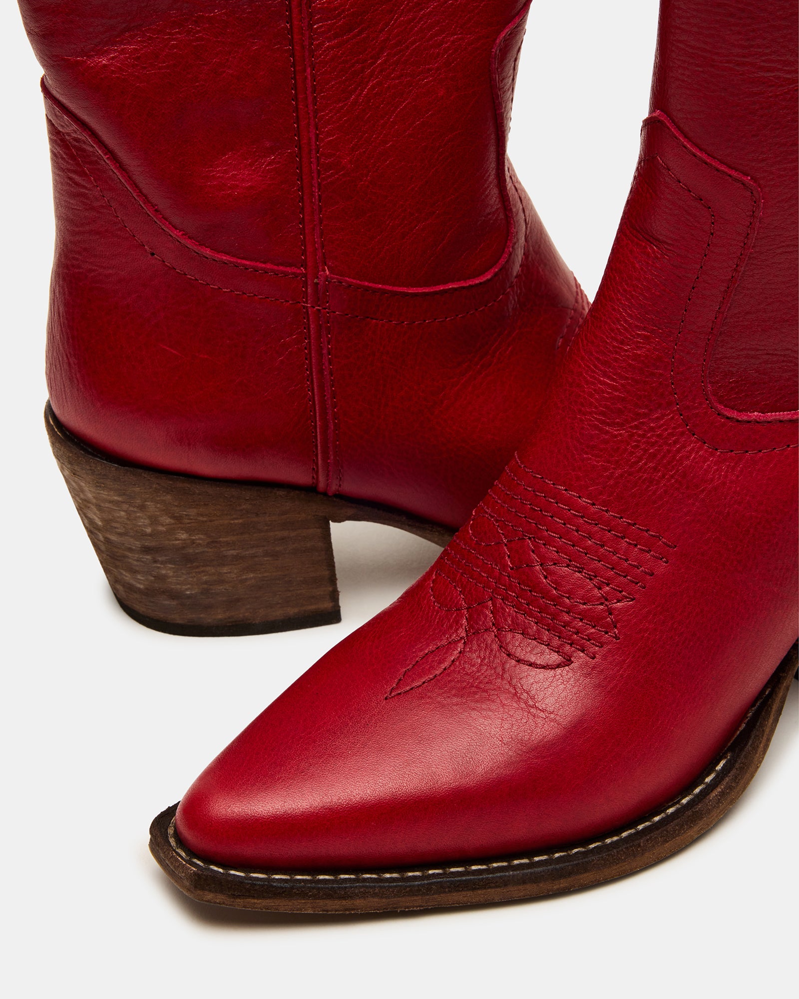 Side angle of red leather Western boots showing pointed toe and stacked heel.