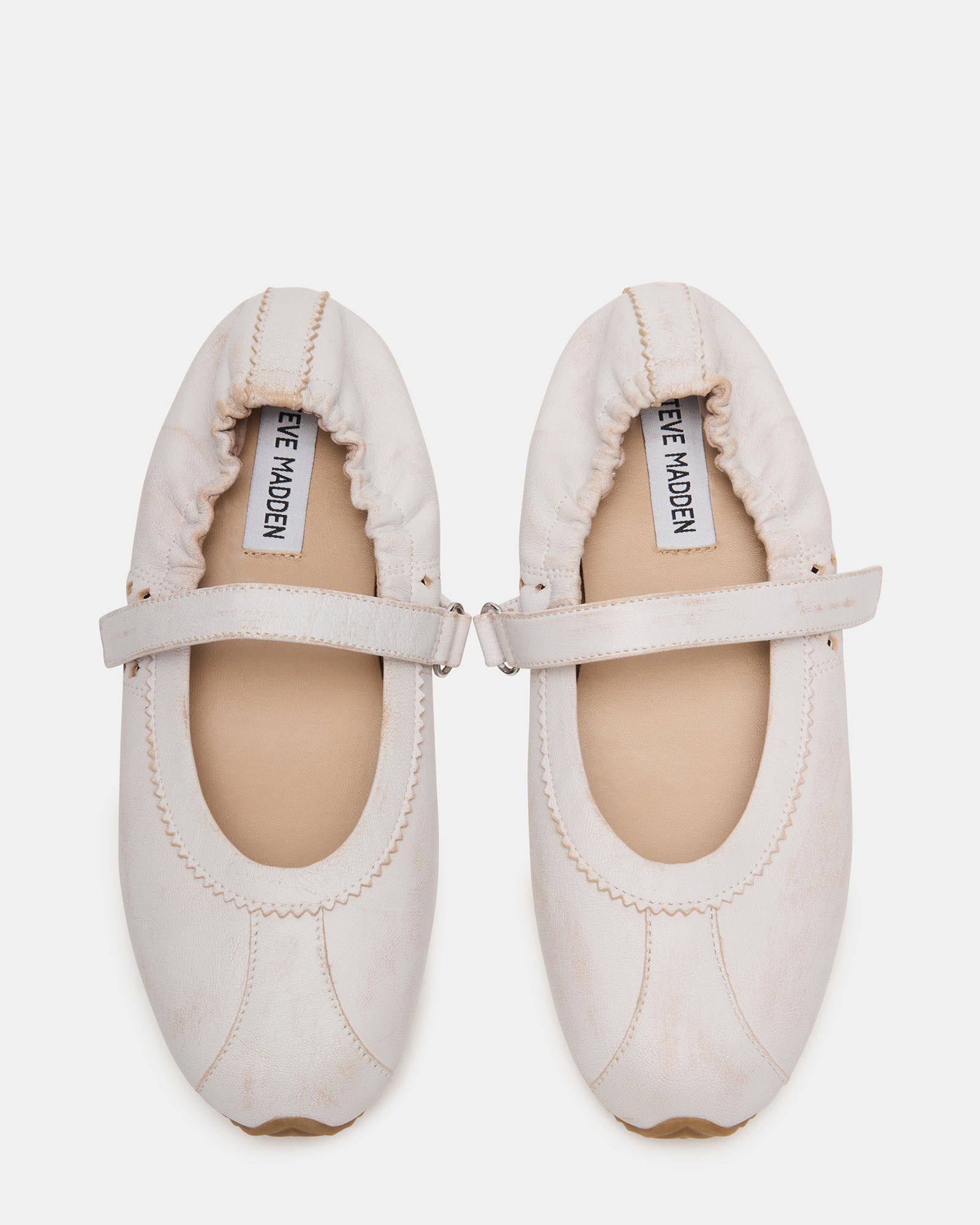 Side view of white ballet ballerina flats with Mary Jane strap on hardwood floor