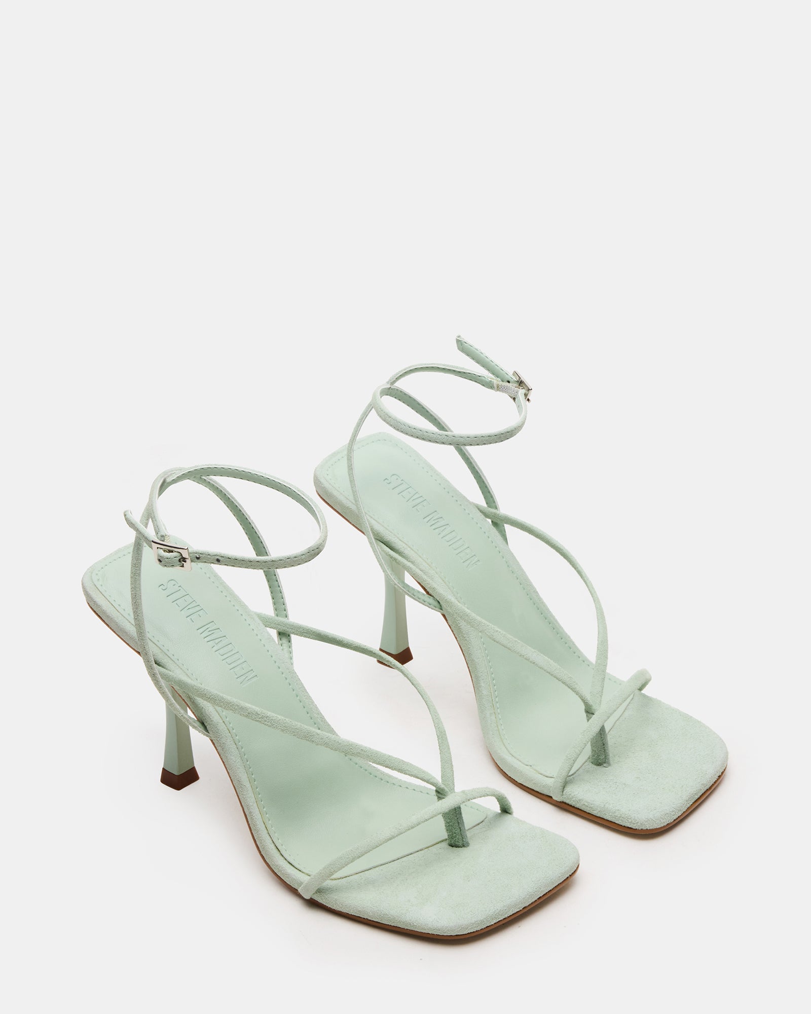 Pair of white strappy heels styled for an evening look with a chic dress