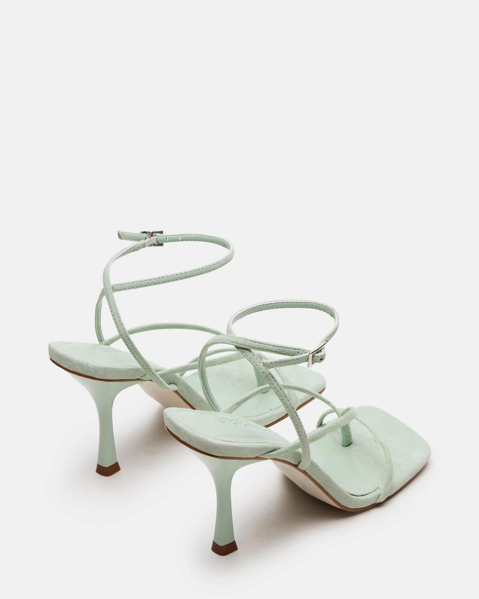 Pair of white strappy heels styled for an evening look with a chic dress