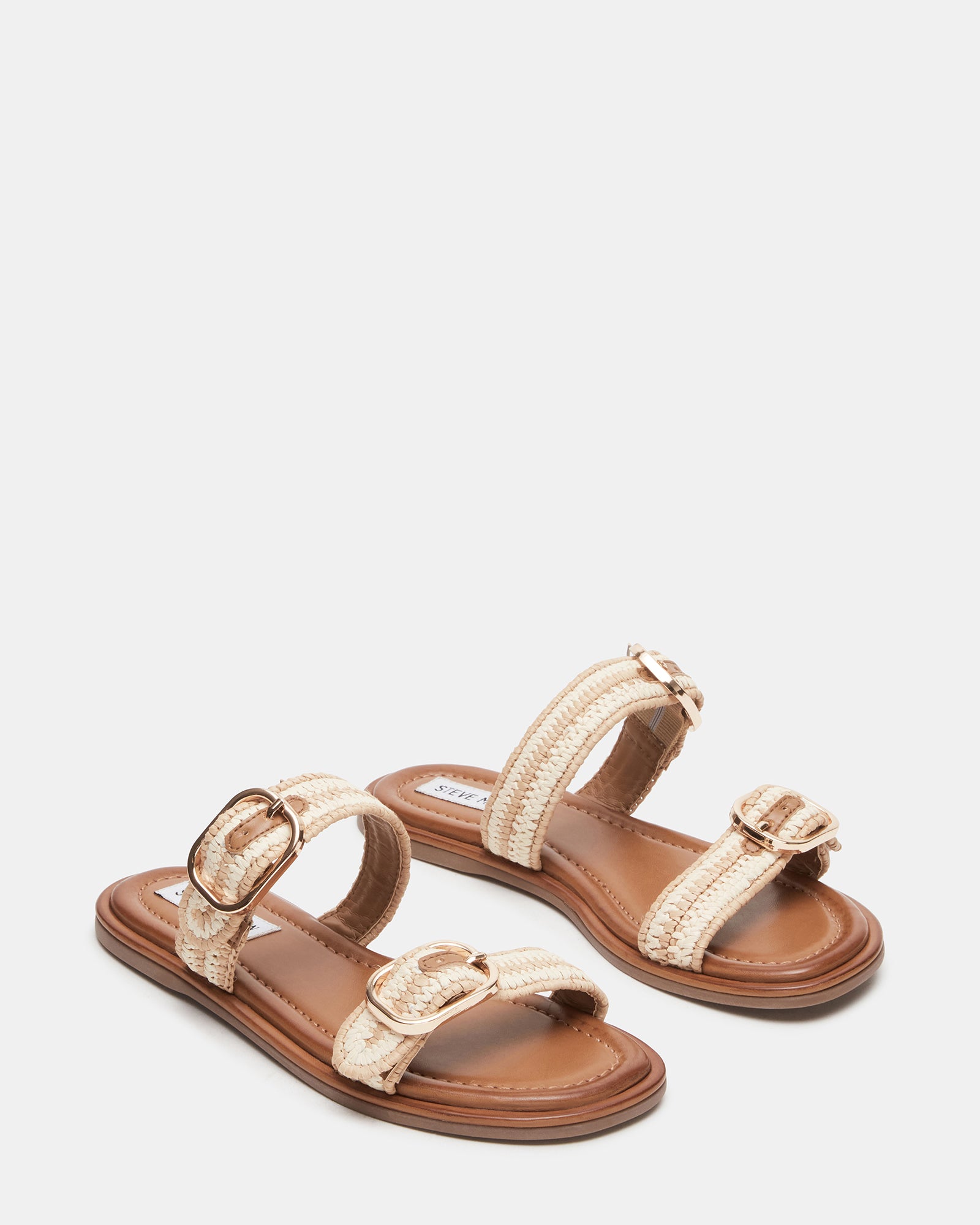 Close-up of the gold flat sandals highlighting the buckle detail.