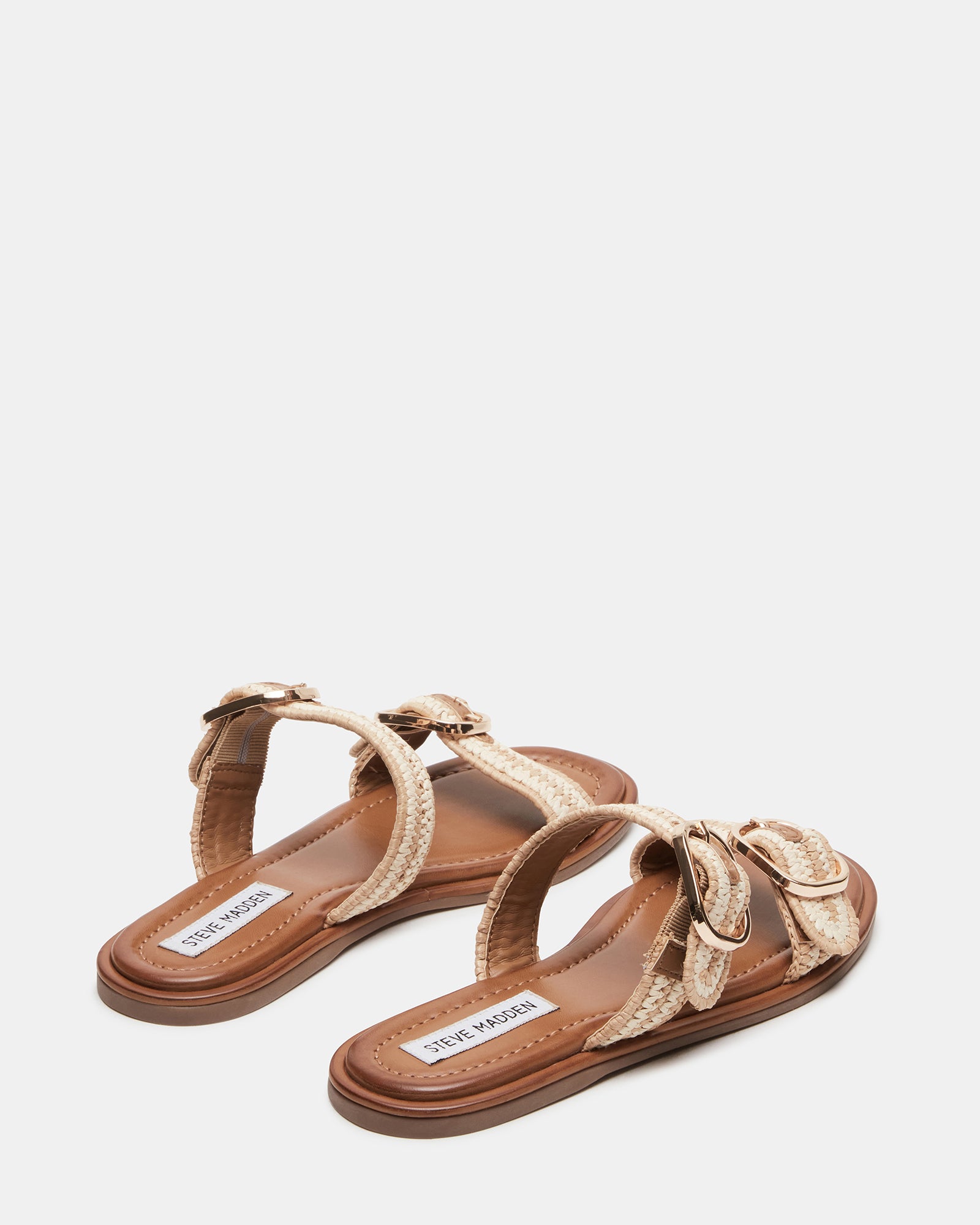 Close-up of the gold flat sandals highlighting the buckle detail.