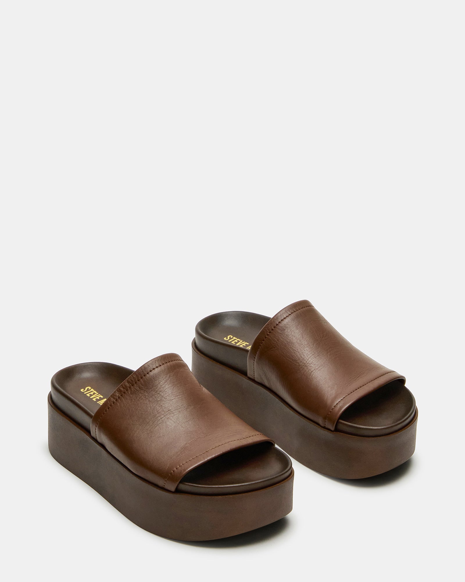 Model wearing Arwen brown leather slide sandals, styled for a summer outing.