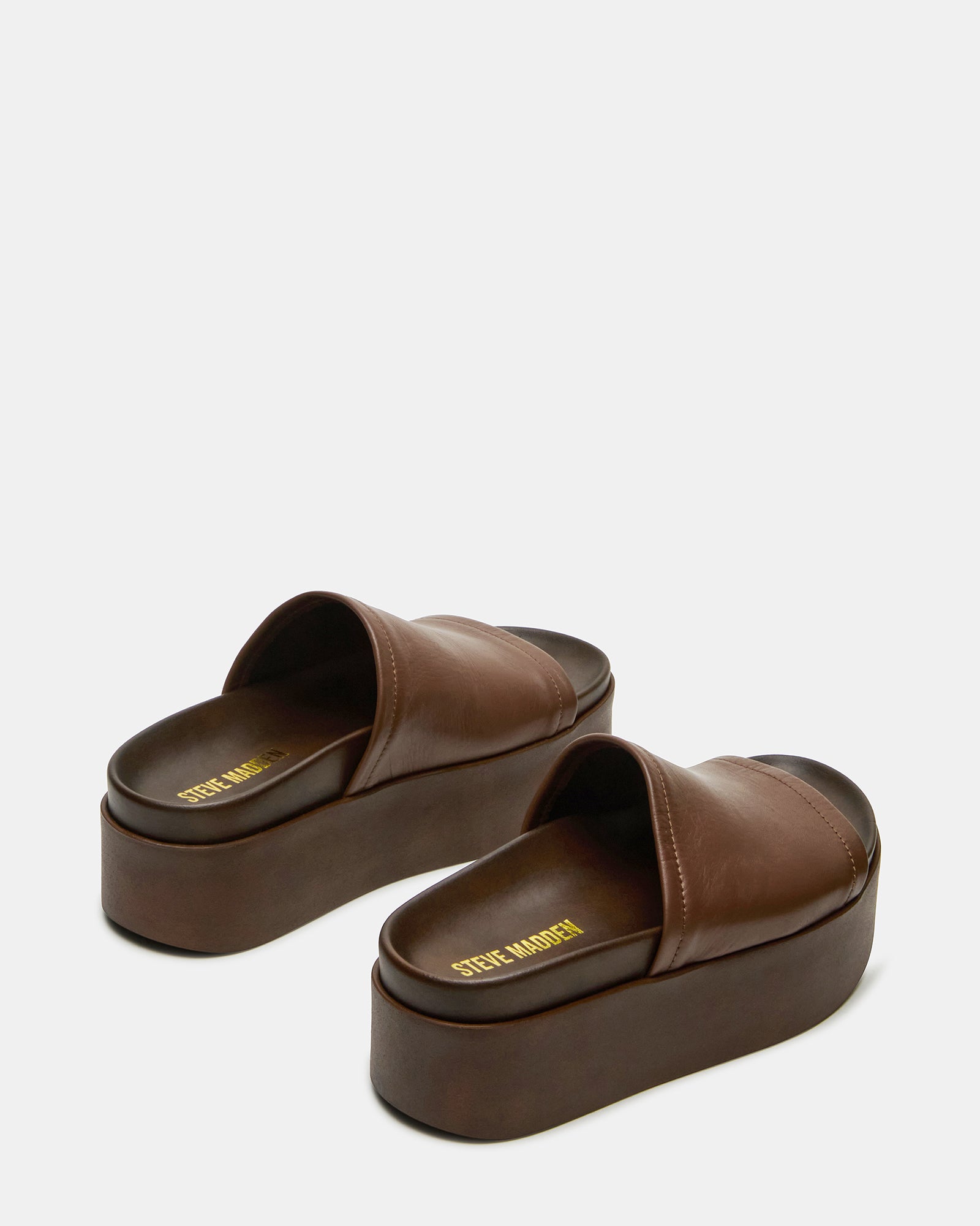 Model wearing Arwen brown leather slide sandals, styled for a summer outing.