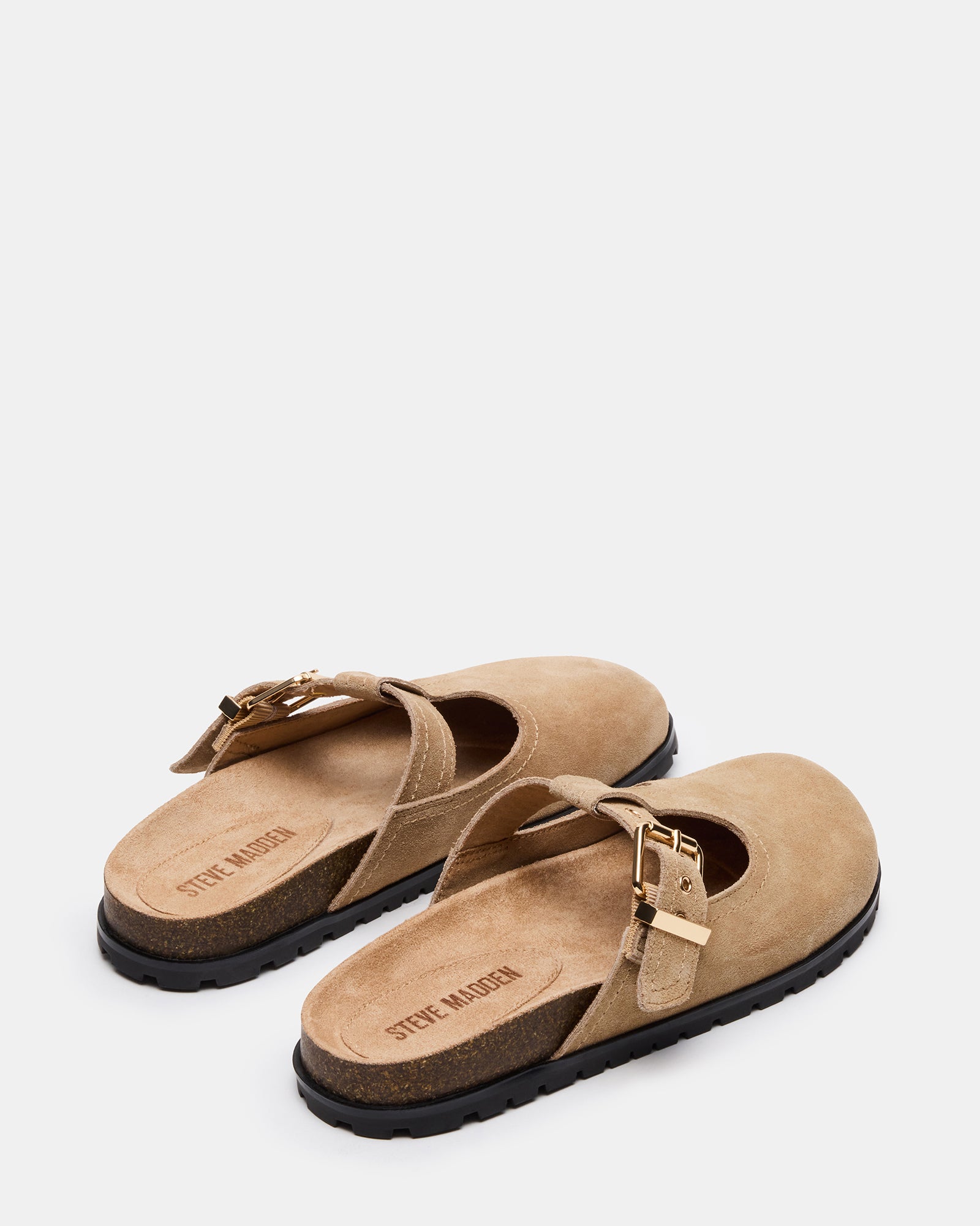 Taupe suede mules with buckle detail on a models feet, showcasing stylish clog shoes.