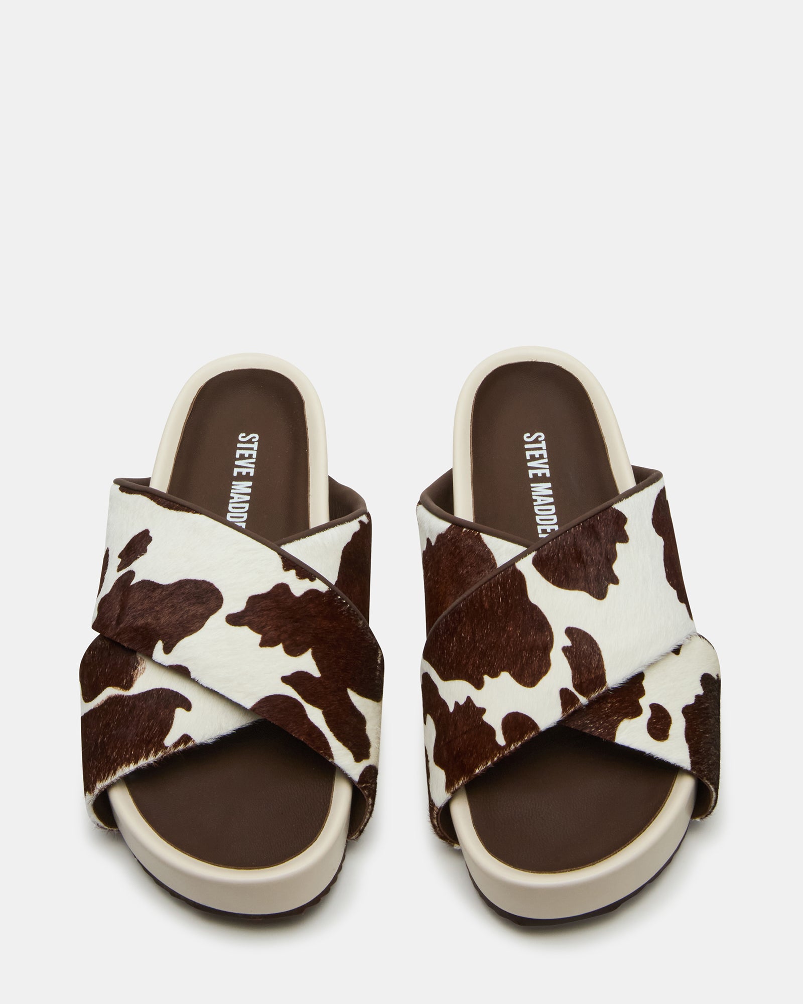 Side view of AVENDRA brown cow print flatform sandals showing the crisscross straps and chunky heel
