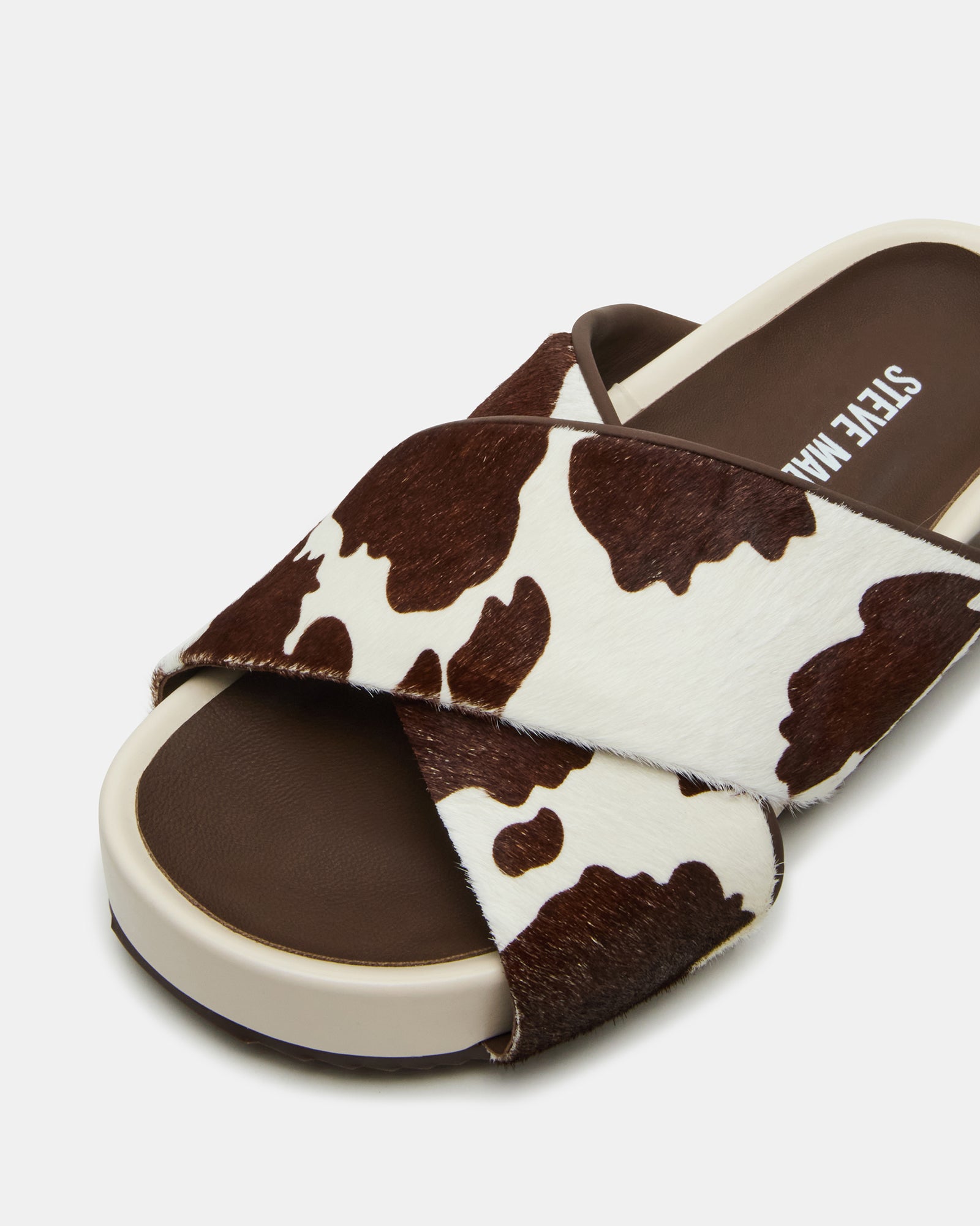 Styled image of women wearing AVENDRA brown cow print flatform sandals paired with casual summer attire