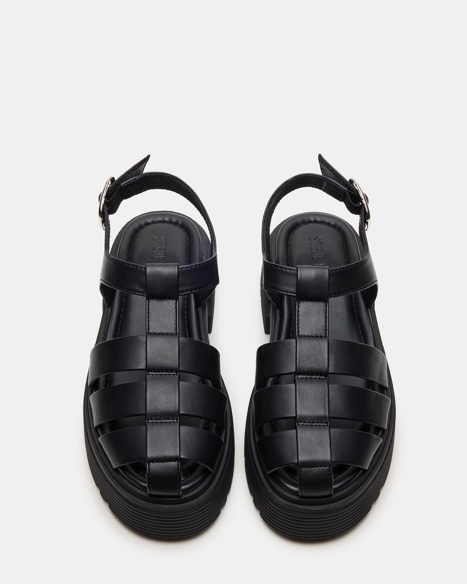 Black fisherman sandals on a sandy beach, showcasing height and comfort.