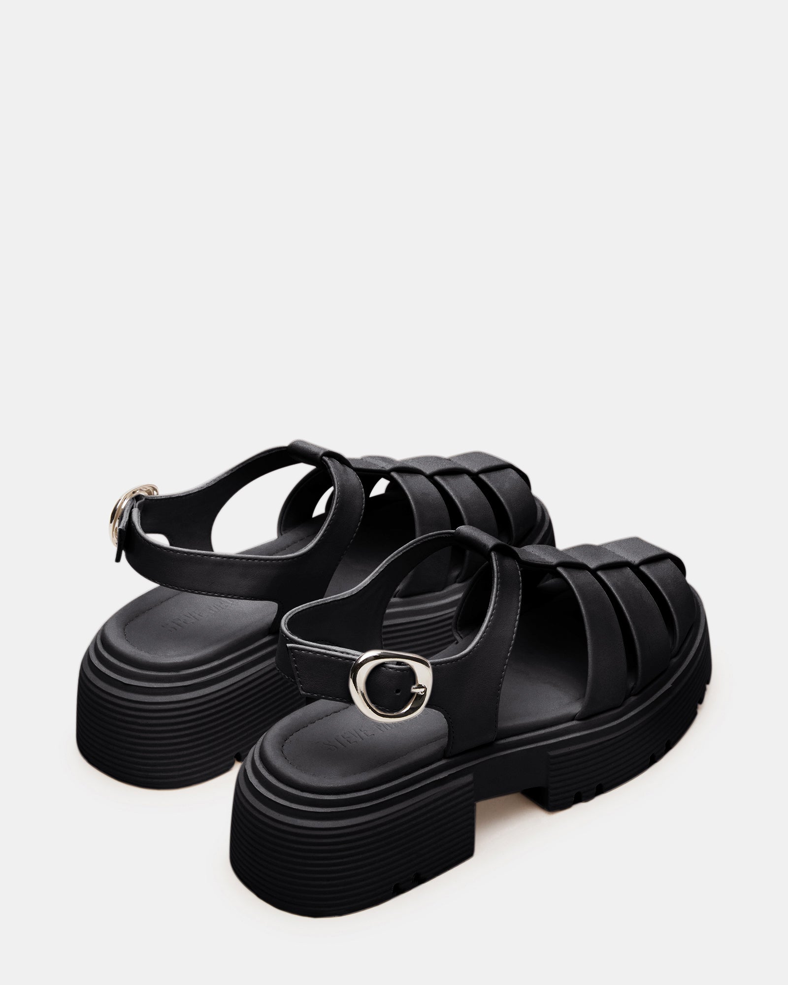 Close-up of white platform sandals against a vibrant city background.