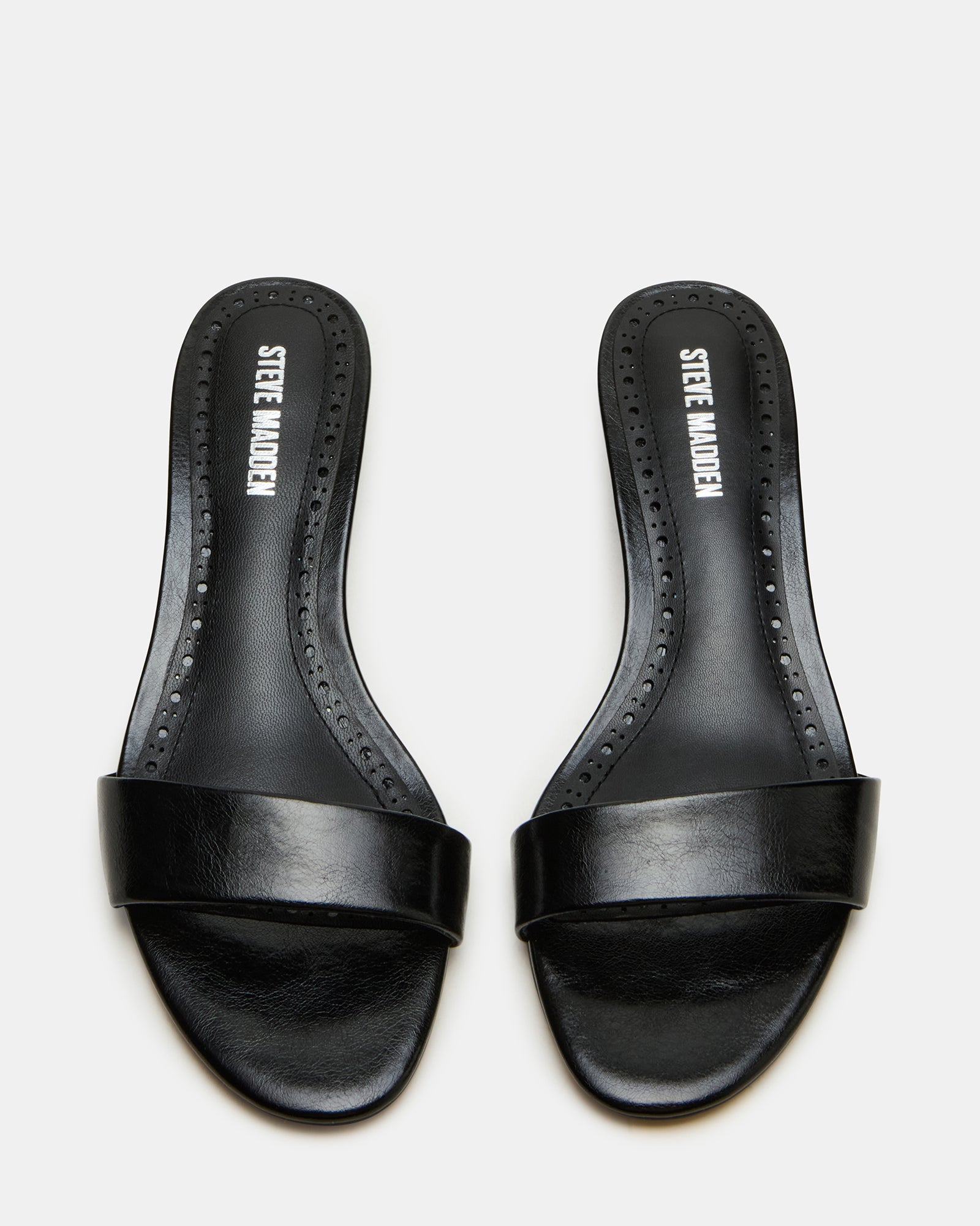 Side view of BERRY black vegan mule heels with kitten heel on a city street