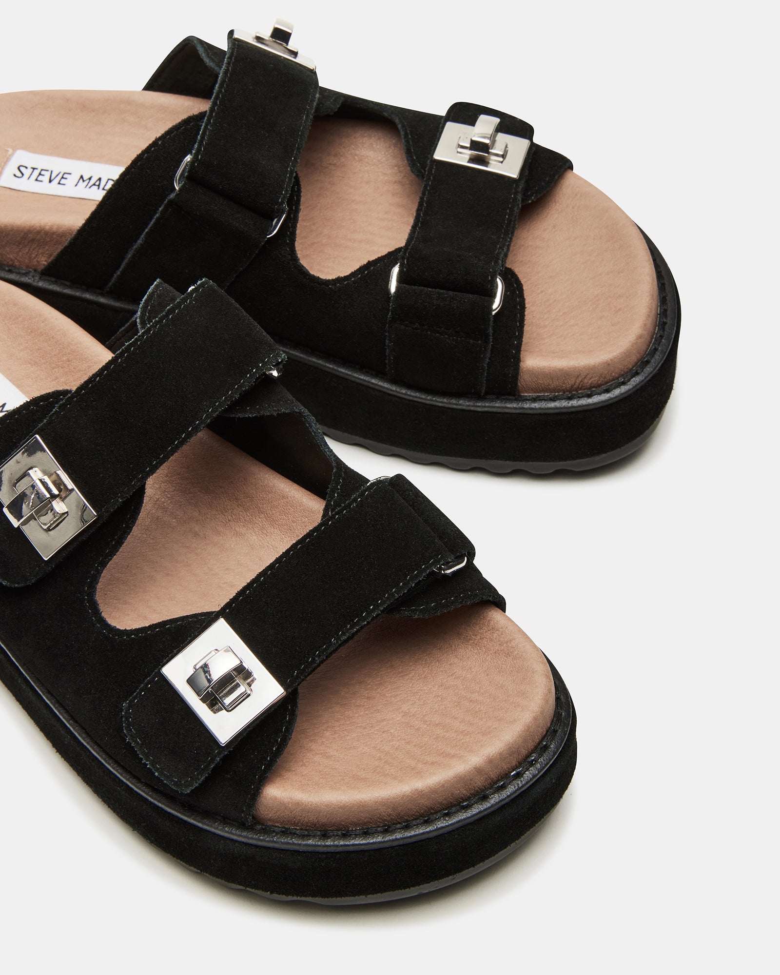 Walking scene of a woman wearing black suede flatform sandals on city streets