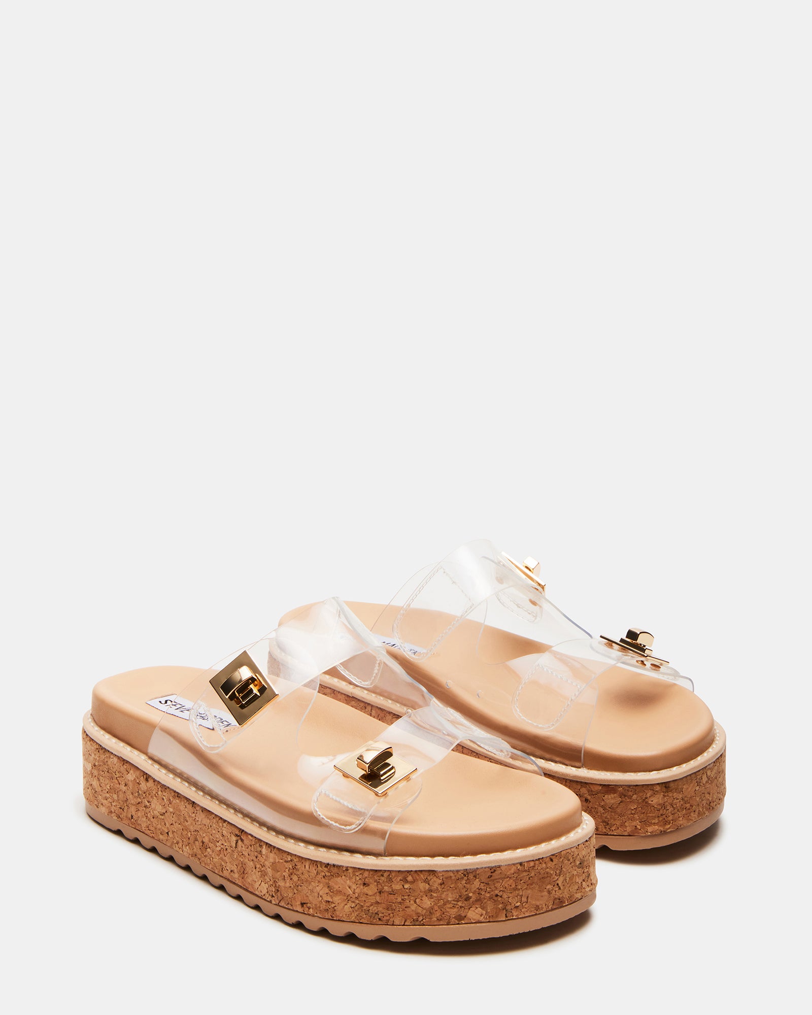White platform sandals showcased against a floral backdrop.