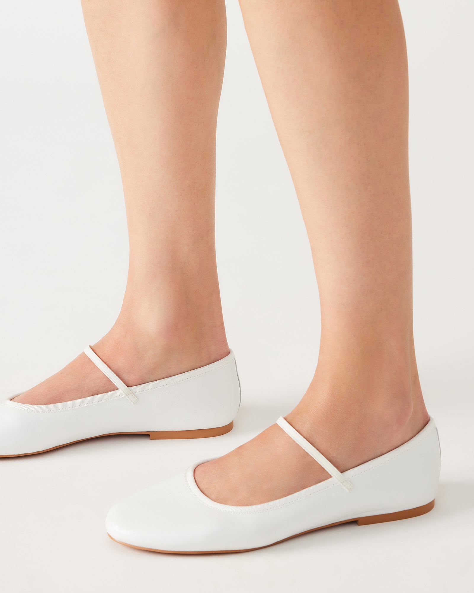 Close-up of the elastic strap on the white leather flats, perfect for casual outings.