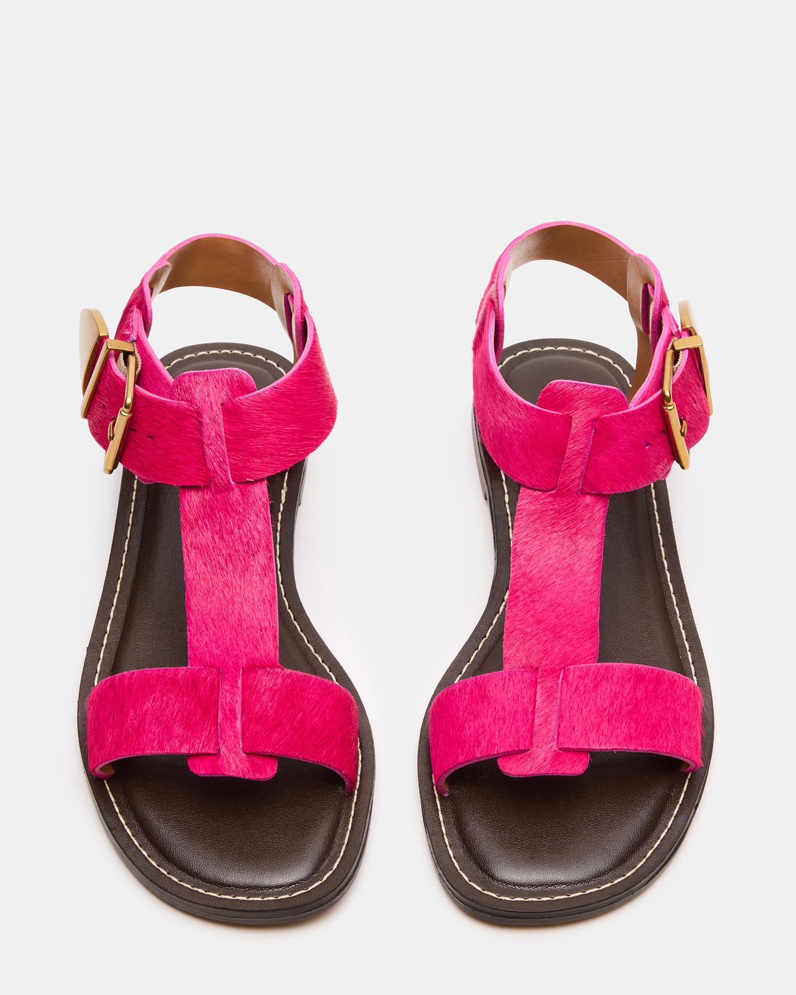 Hot pink leather flat sandals with ankle strap on a models feet, perfect for summer outings