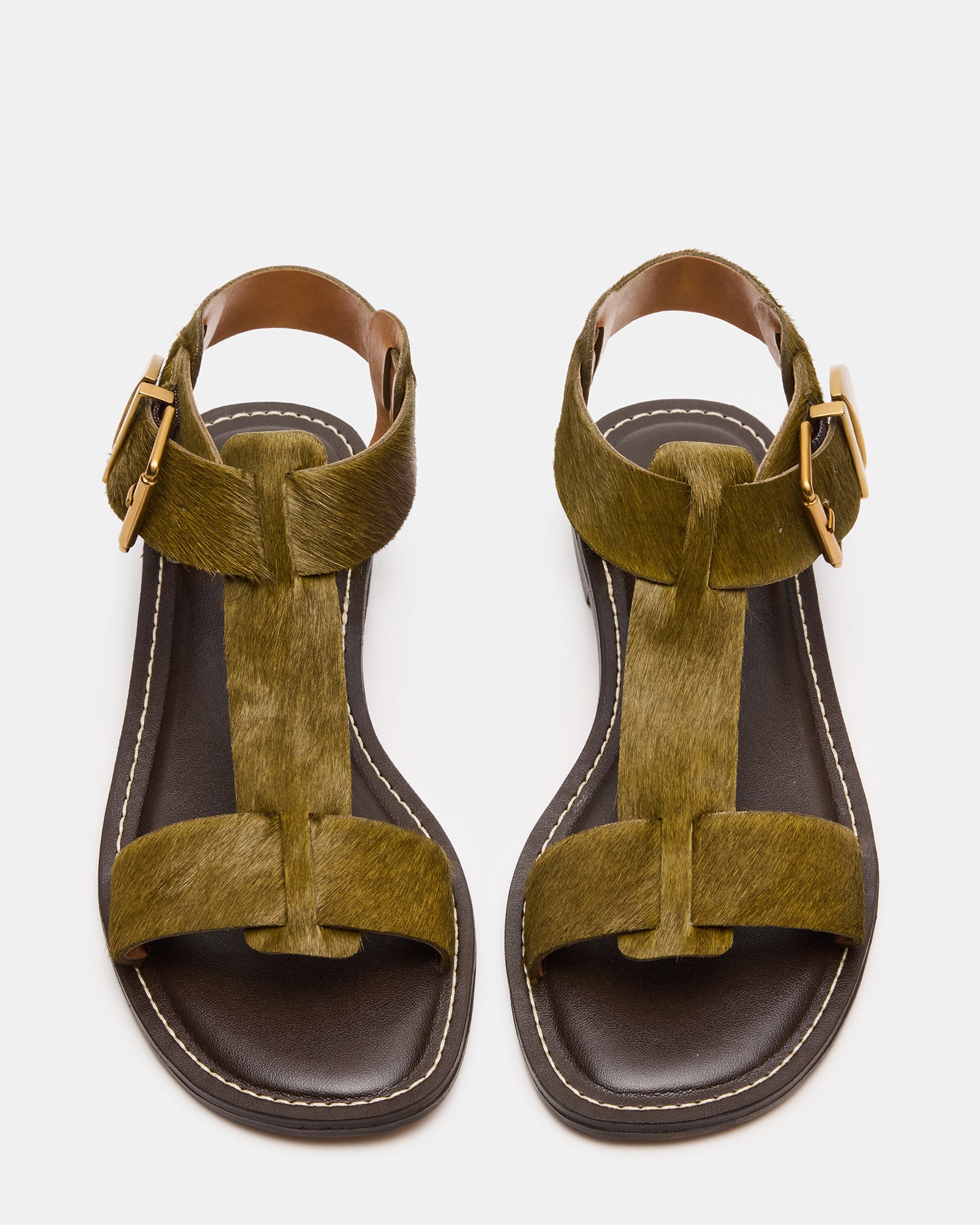 Top-down image of olive BRAZINN flat sandals on a rustic wood surface.