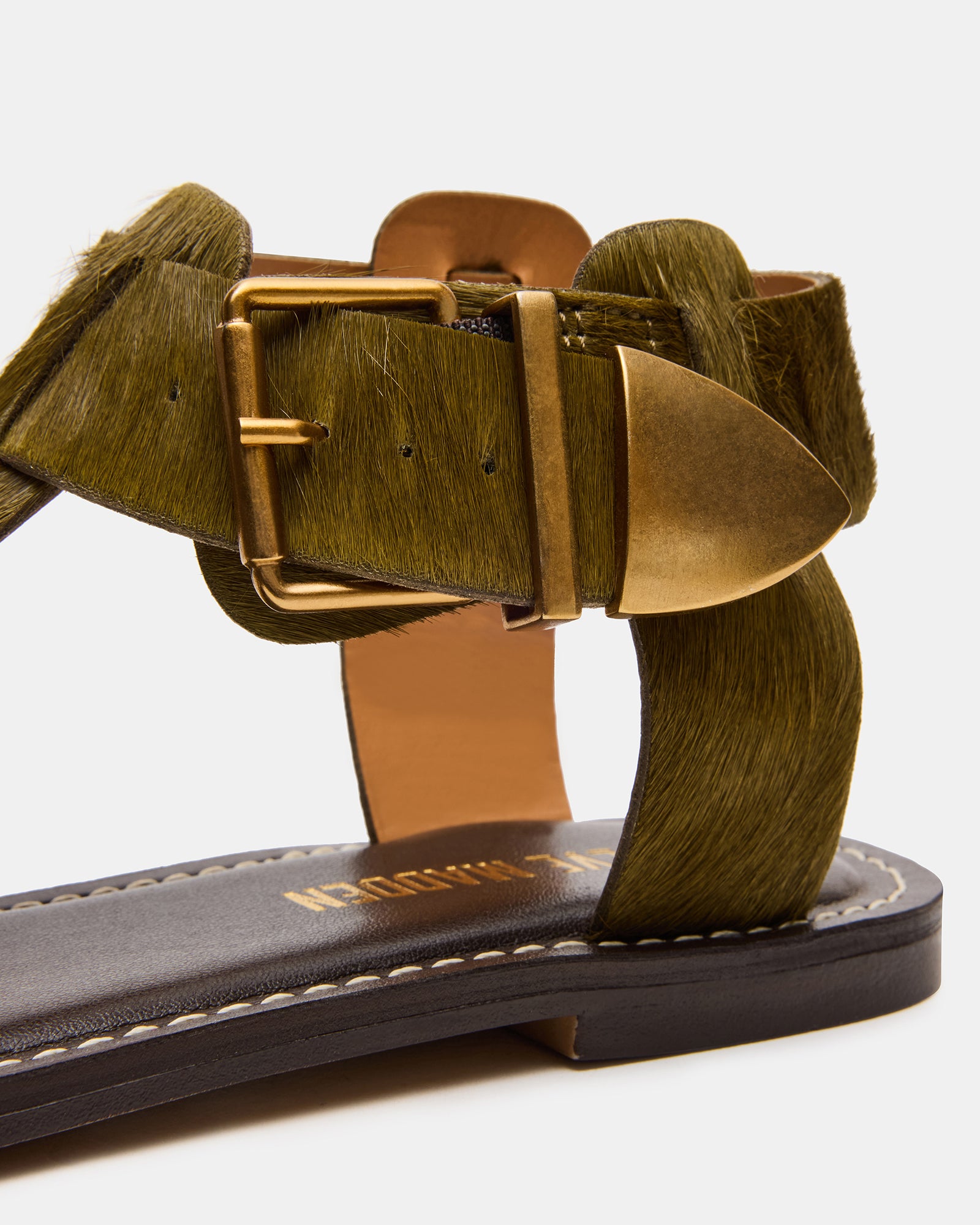 Lifestyle photo of the black flat sandals version being worn on a coastal boardwalk.