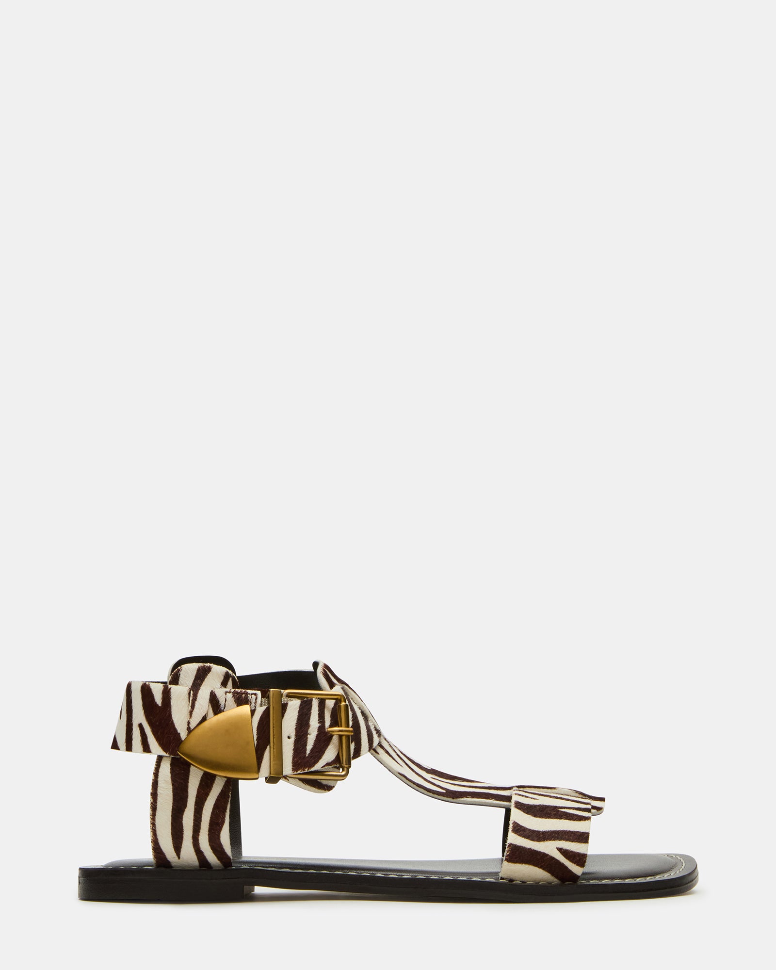 Side view of BRAZINN zebra flat sandals with ankle strap on a summer outdoor setting