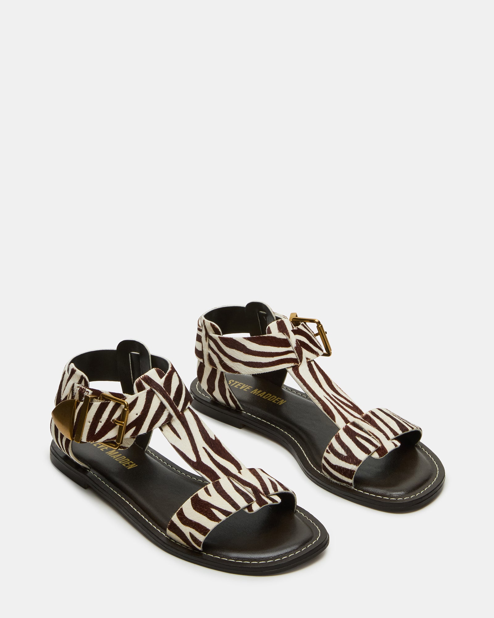Fashionable zebra print flat sandals with strappy design on a woman’s feet