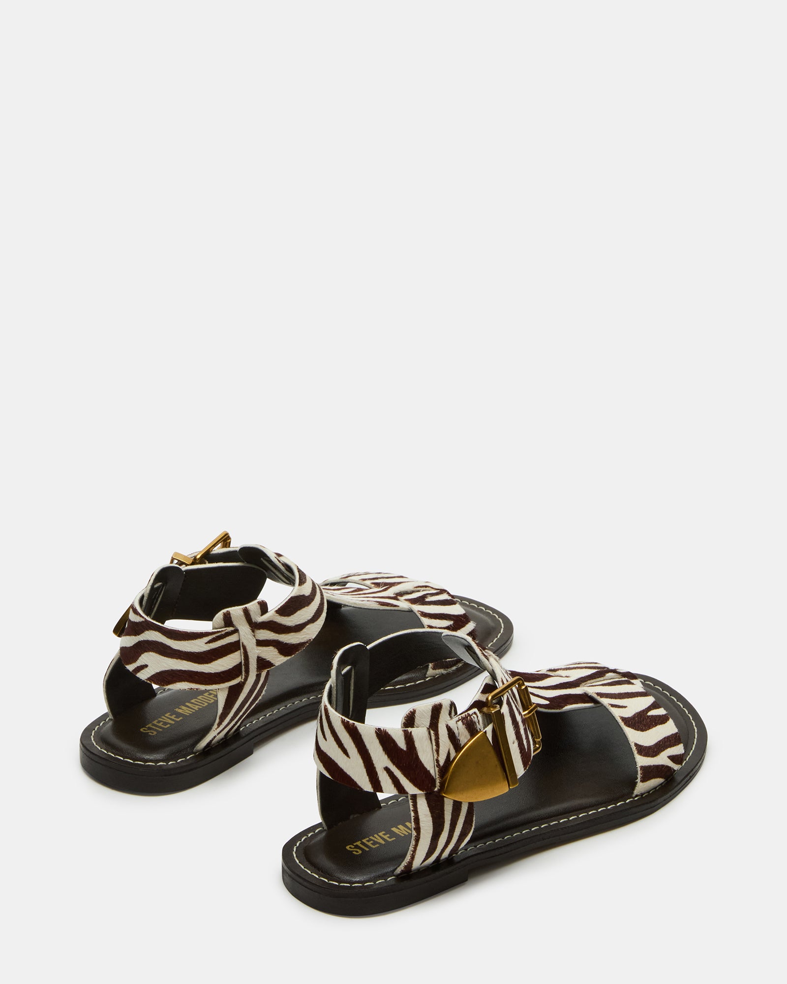 Fashionable zebra print flat sandals with strappy design on a woman’s feet